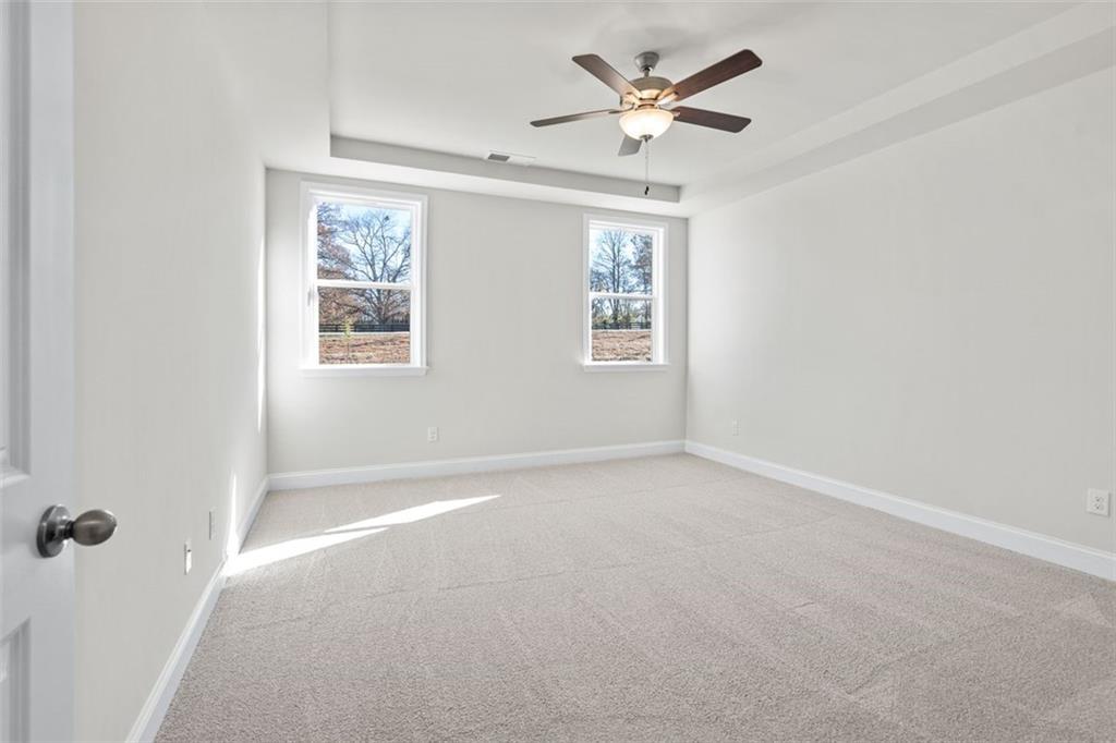 Bright bedroom with ceiling fan, large windows, and plush carpet in Davidson Homes The Ash C at Wehunt Meadows, Hoschton
