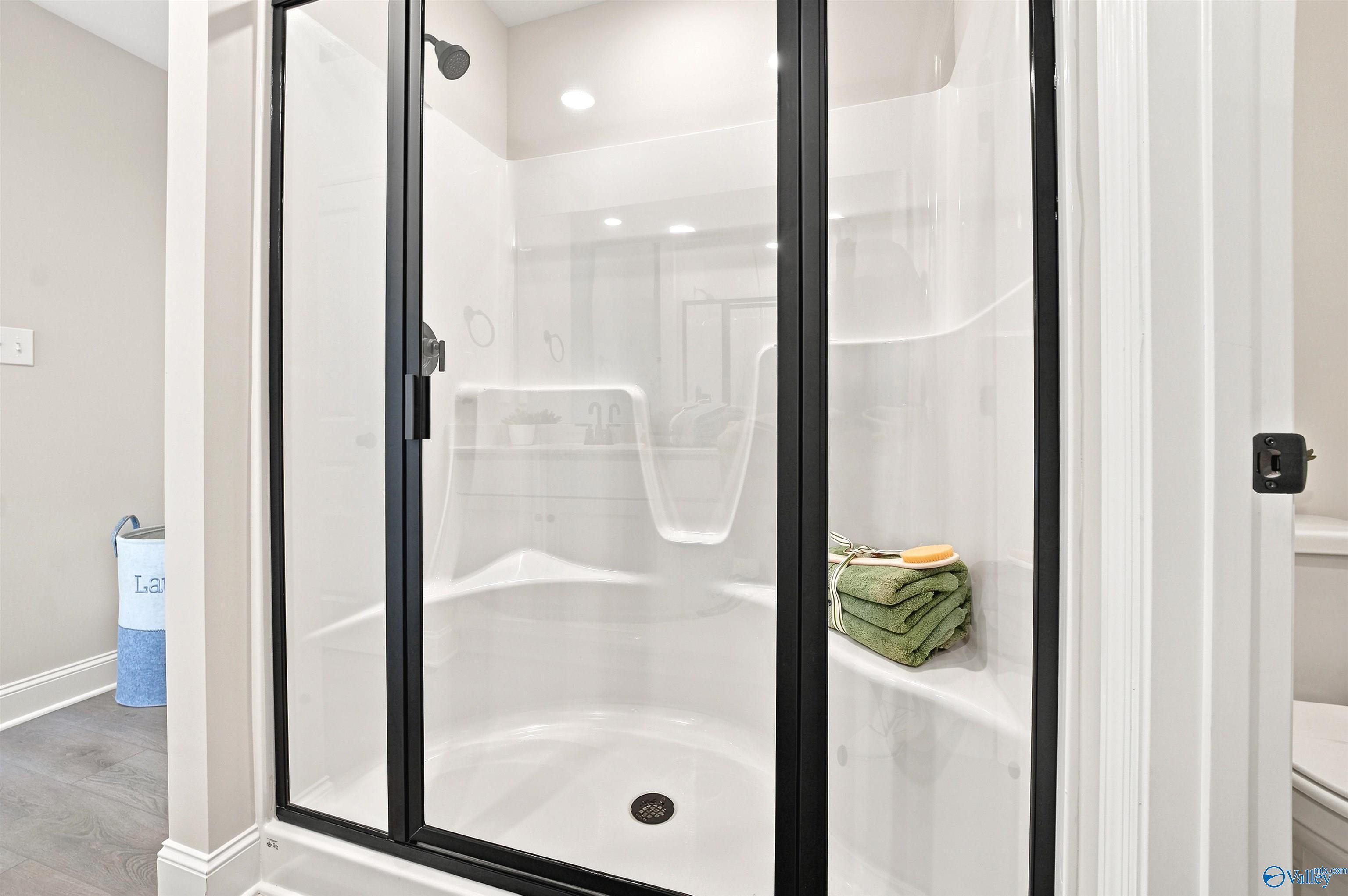 Modern walk-in shower with black frame in The Burton B floor plan at Heritage Lakes, New Market, Alabama.