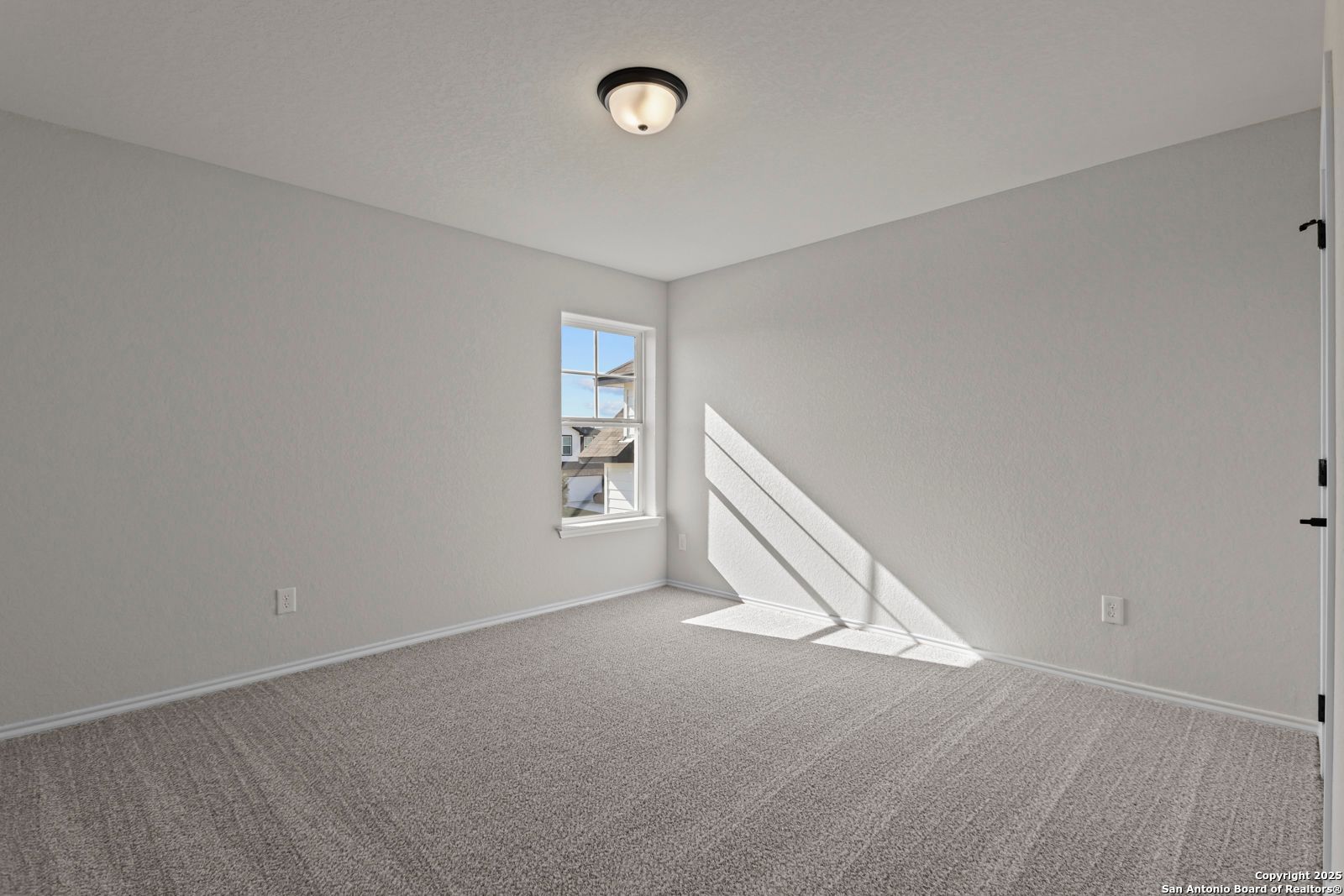 Bright secondary bedroom with gray walls, carpet flooring, and sunlit window in Davidson Homes The Douglas C, Seguin, Texas