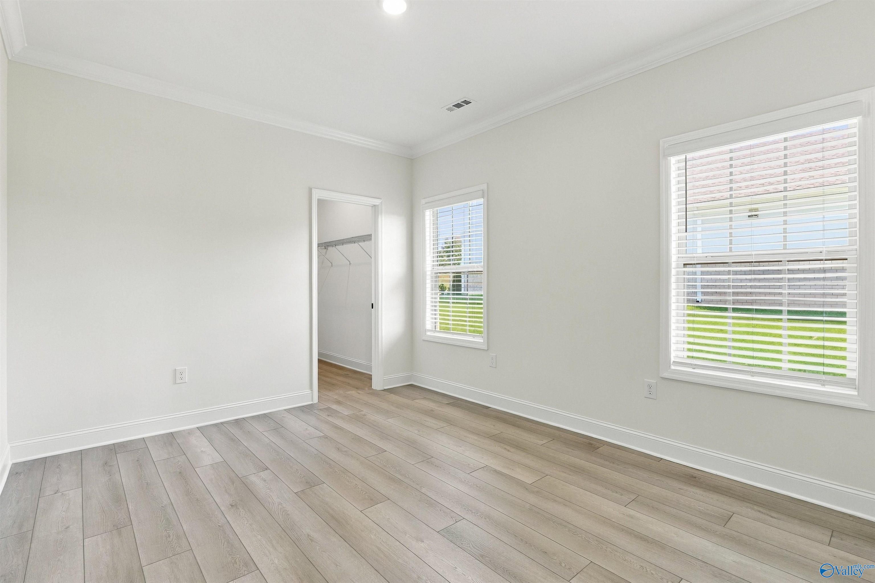 Bright bedroom with luxury vinyl plank flooring, white walls, and shuttered windows in Davidson Homes' Valencia plan, Huntsville
