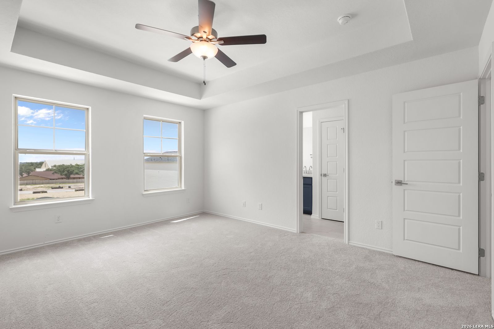 Bright bedroom with tray ceiling and ceiling fan in The Gillian C floor plan at Meadows at Oak Creek, San Antonio, Texas.