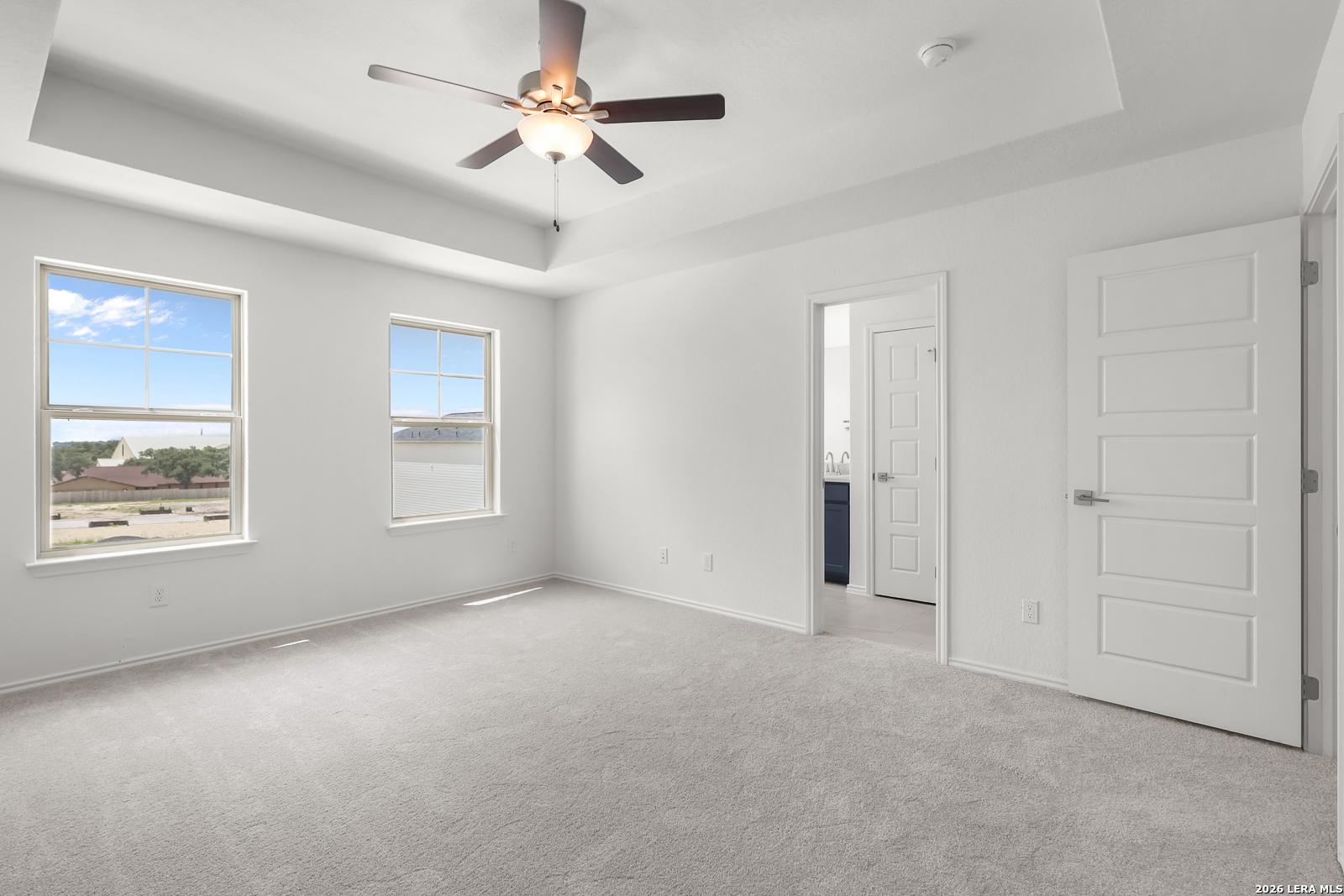 Bright bedroom with tray ceiling and ceiling fan in The Gillian C floor plan at Meadows at Oak Creek, San Antonio, Texas.