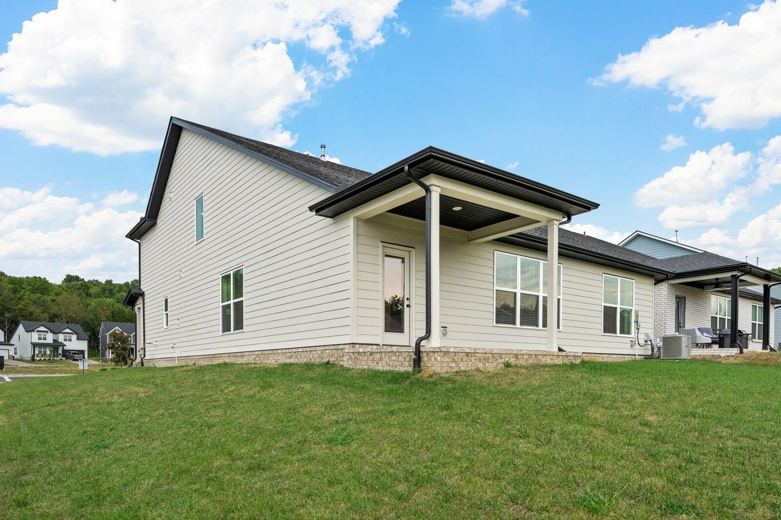 Two-story Ridgeport home exterior with white siding, black roof, covered porch on grassy lot in Carellton, Gallatin, Tennessee