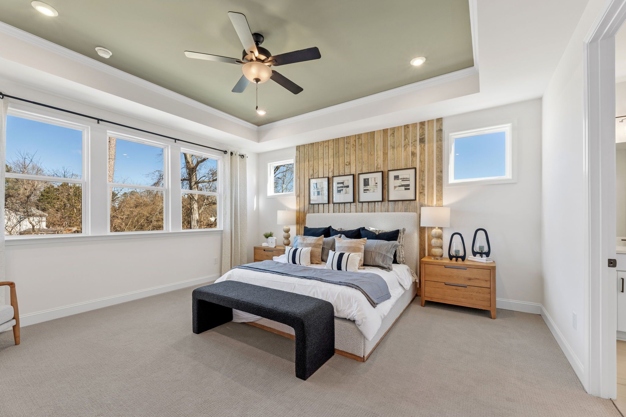 Spacious primary bedroom at Fern Hollow in Buford GA with king bed wood accent wall ceiling fan and large windows