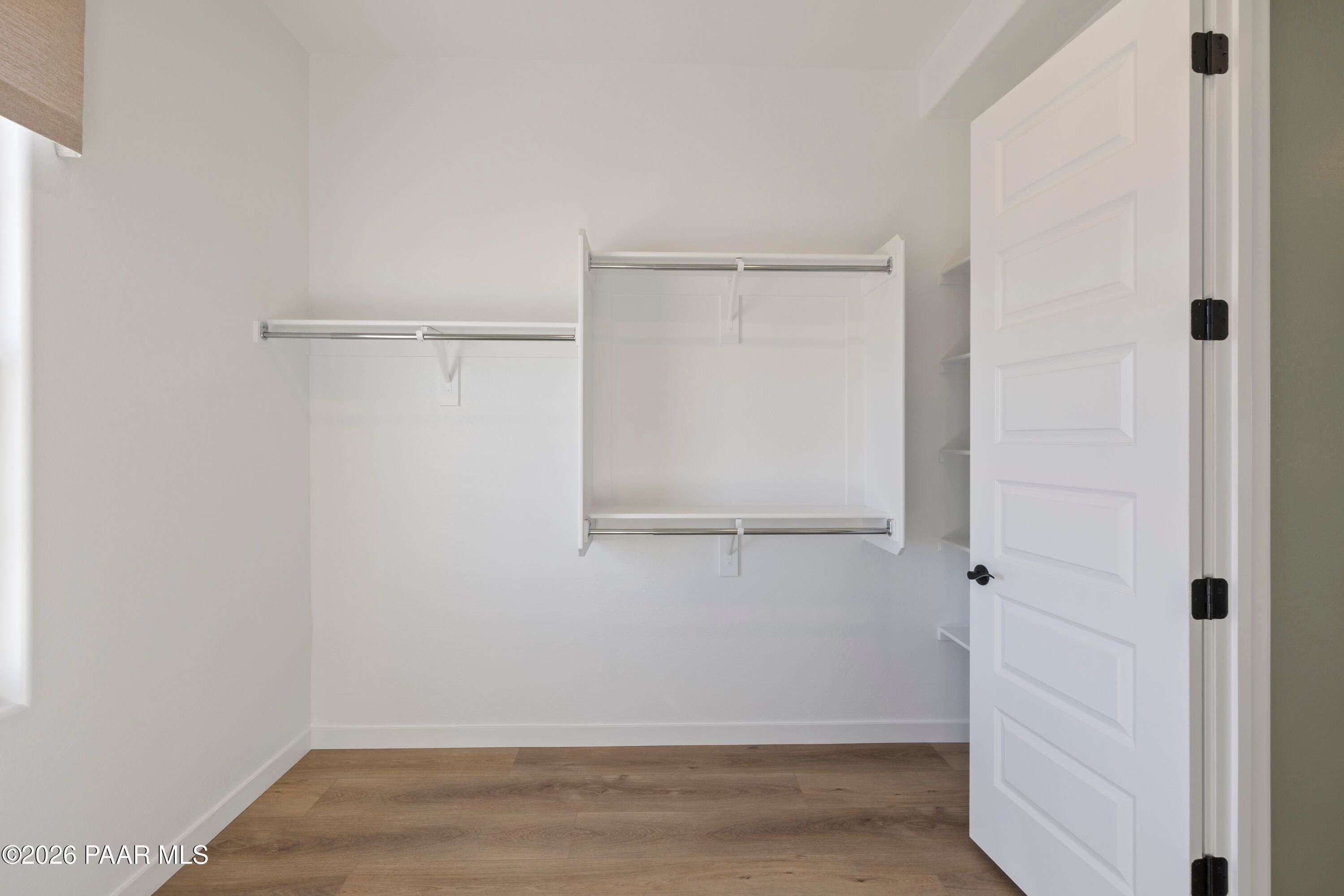 Walk-in closet with white shelving and rods in The Blaze D floor plan by Davidson Homes in Hidden Hills, Prescott, Arizona.