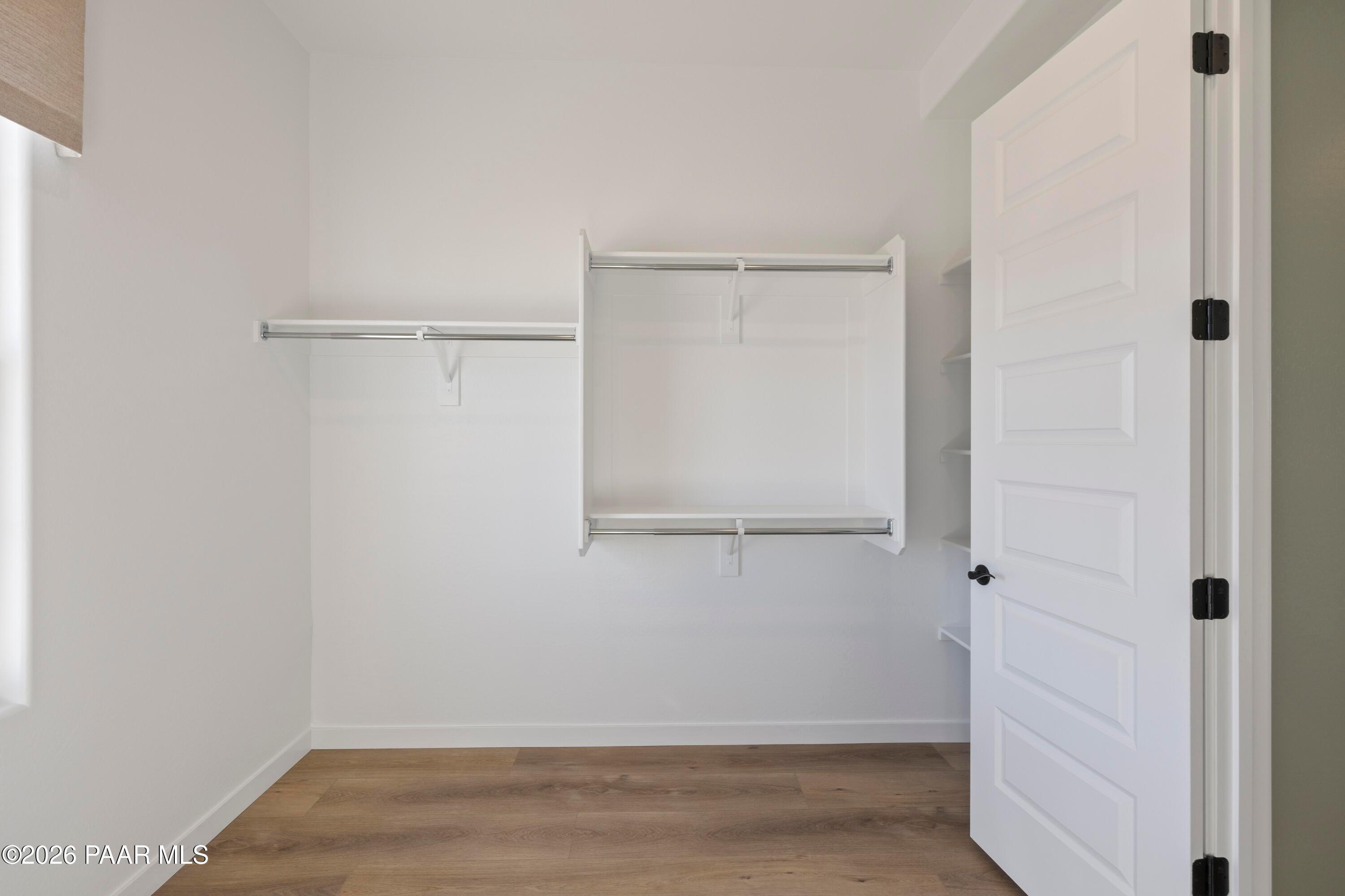 Walk-in closet with white shelving and rods in The Blaze D floor plan by Davidson Homes in Hidden Hills, Prescott, Arizona.