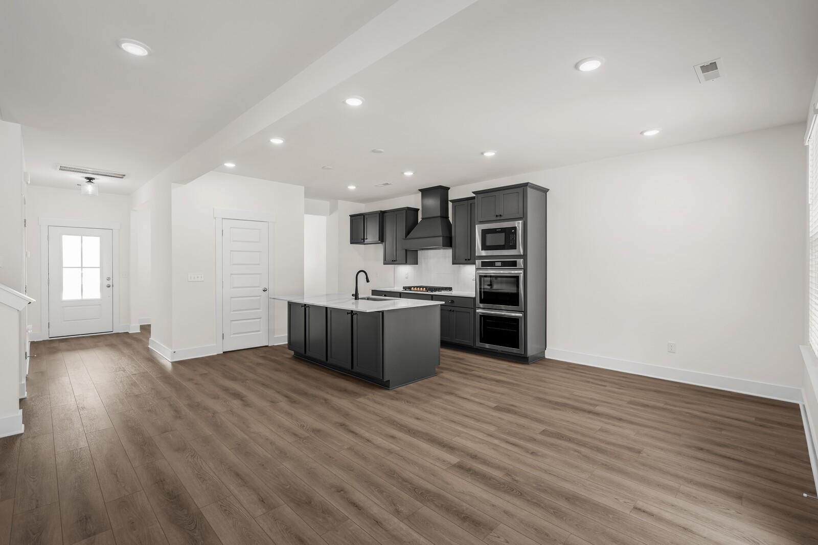 Modern open-concept kitchen with dark gray cabinets and island in The Willow floor plan at Woods Crossing in Gallatin, TN.