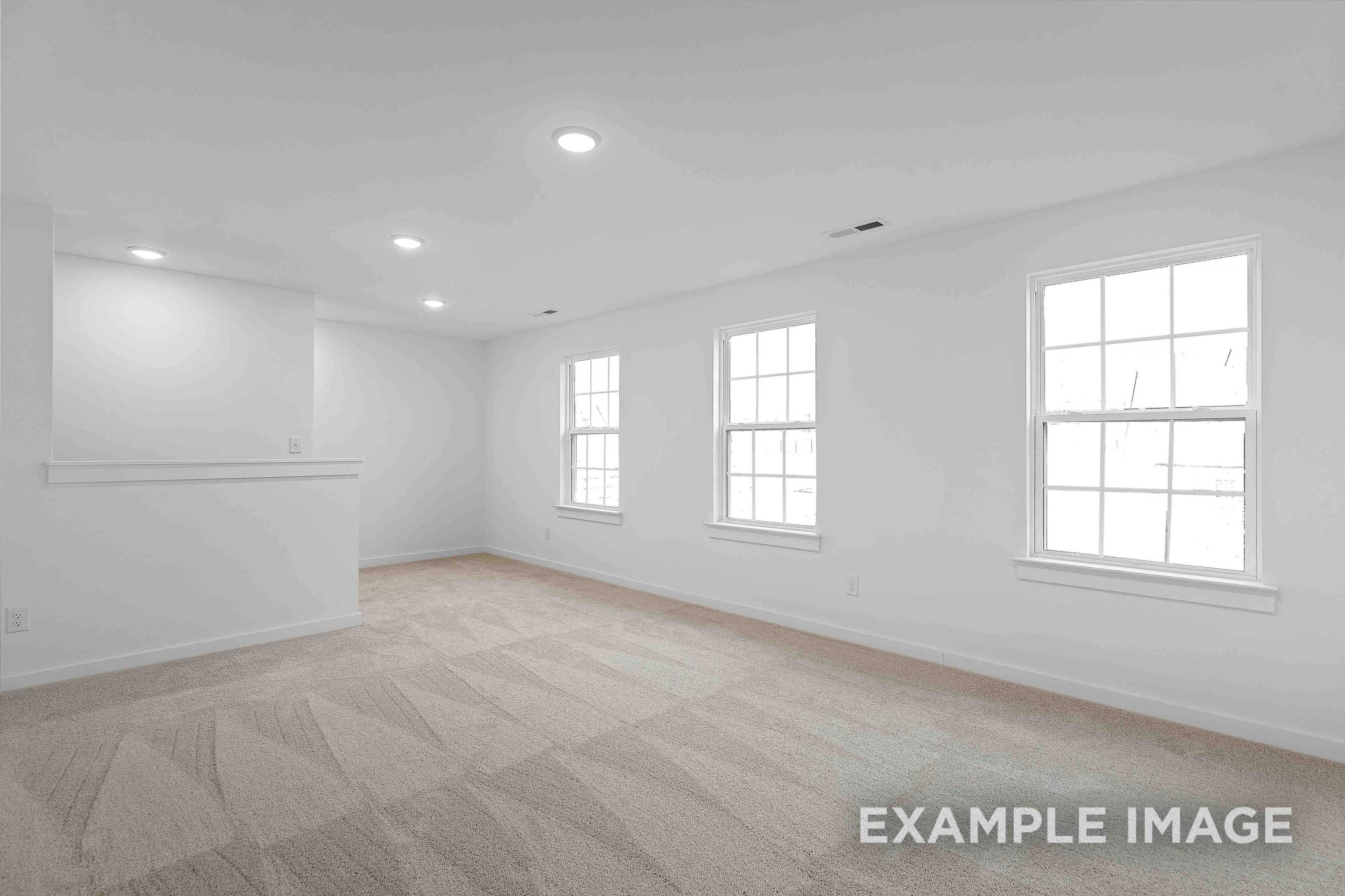 Spacious empty upper-floor bedroom in The Charleston home with white walls, large windows, recessed lights, and built-in shelving