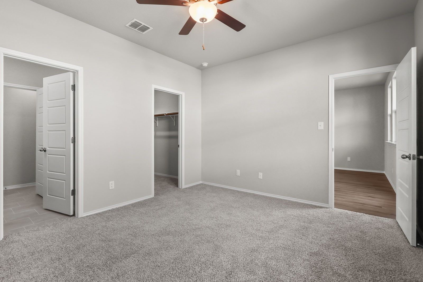 Spacious carpeted bedroom with walk-in closet in The Frio G floor plan by Davidson Homes in Heartland, Texas.