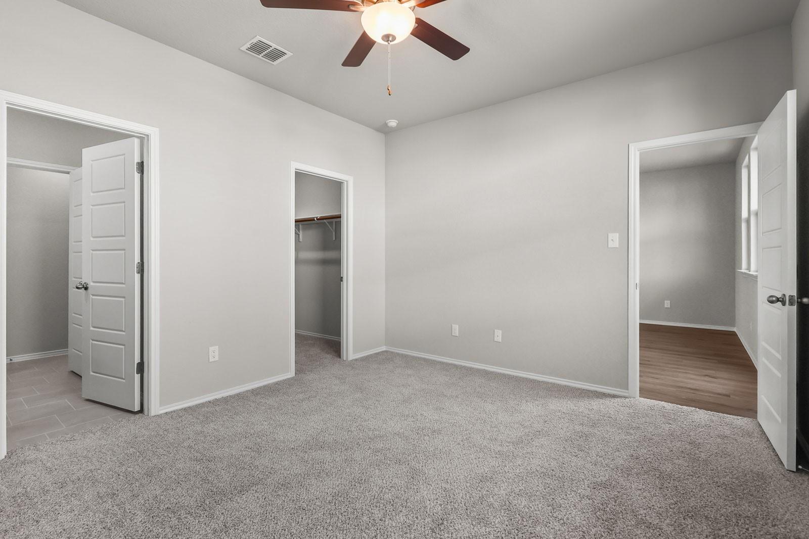 Spacious carpeted bedroom with walk-in closet in The Frio G floor plan by Davidson Homes in Heartland, Texas.