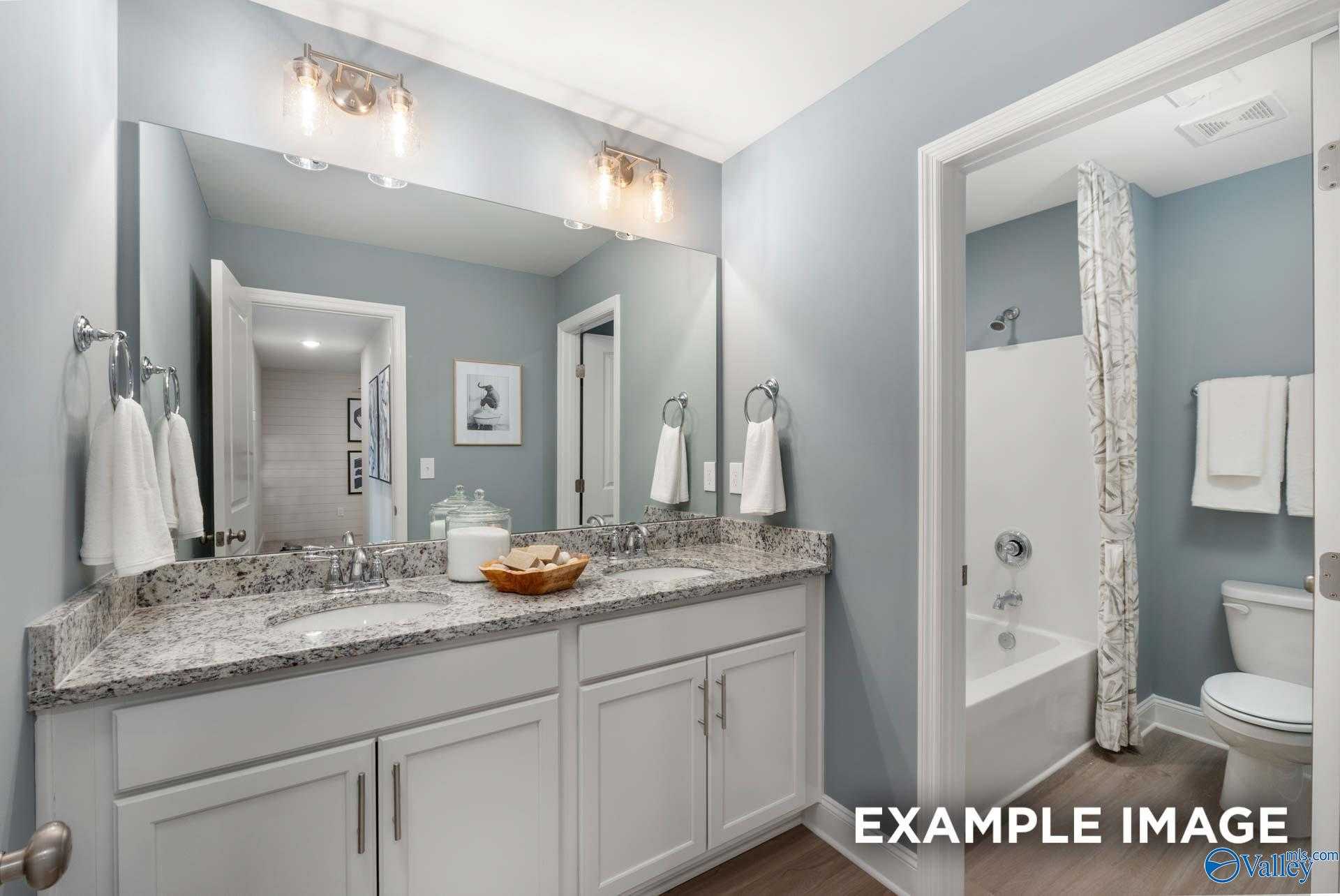 Elegant master bathroom with double granite vanity, tub shower combo, and neutral tones in Davidson Homes The Camden B, Huntsville