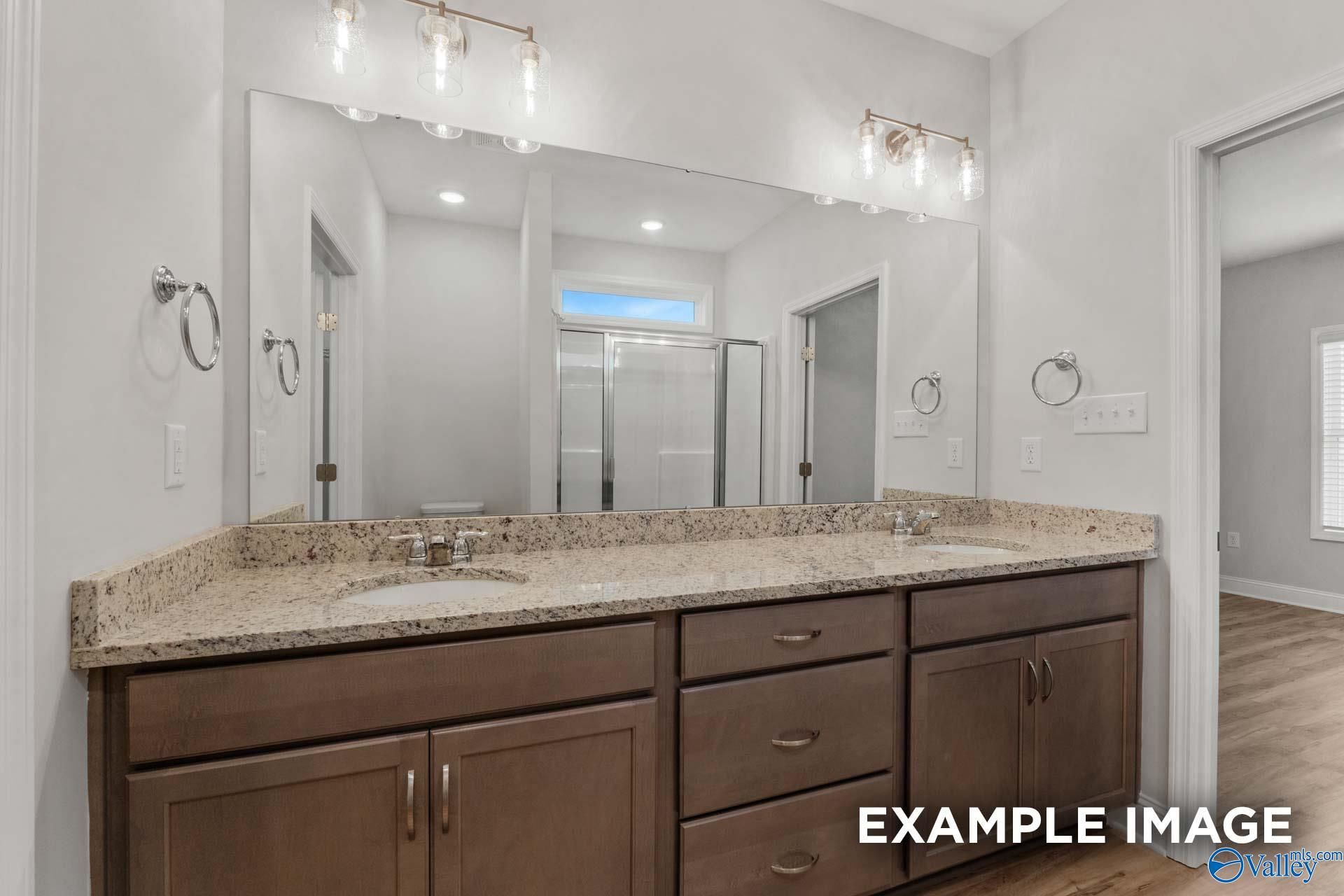 Modern double vanity with granite countertop, dark wood cabinets, and mirrors in master bath of Davidson Homes The Cumberland B, Decatur, Alabama