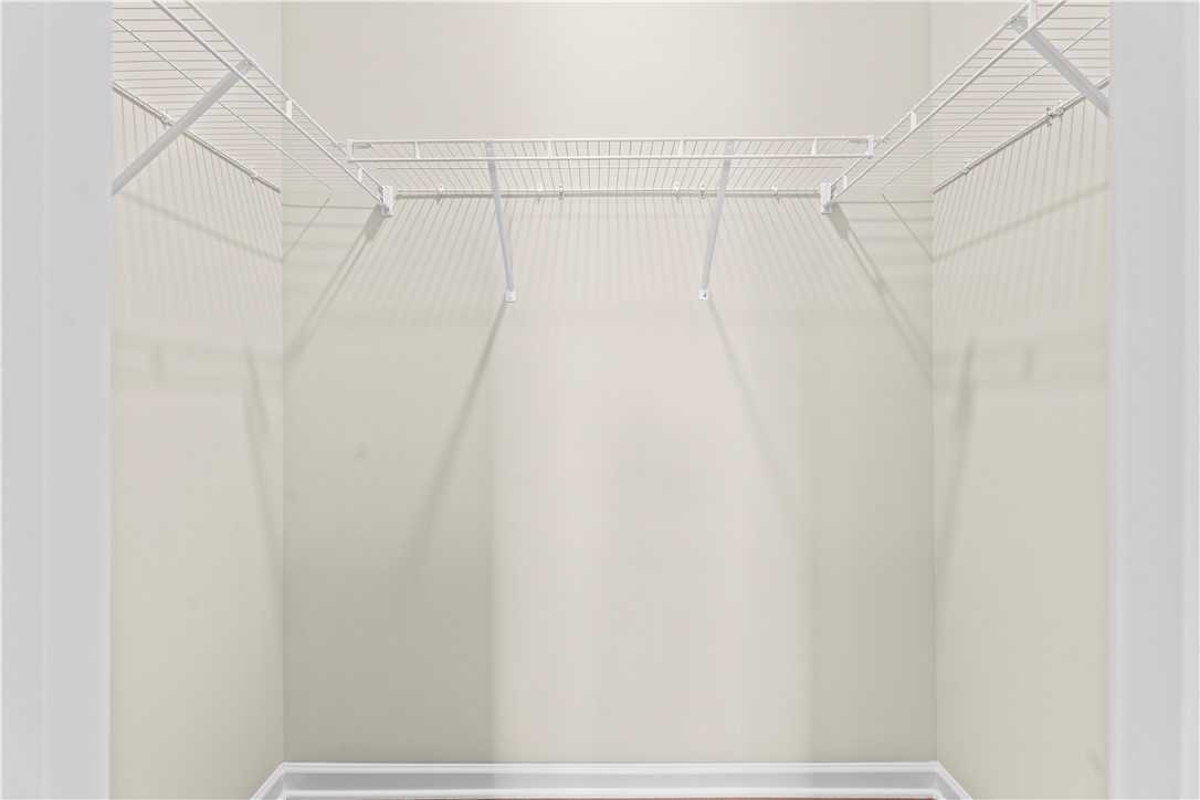 Spacious walk-in closet with white wire shelving and beige walls in Evermore Homes The Orion, Cusseta, Alabama