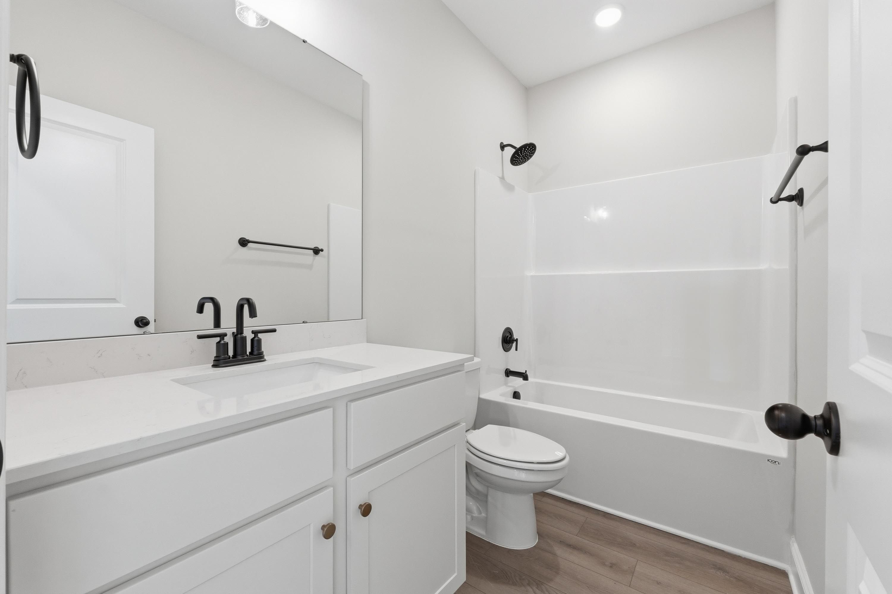 Modern bathroom in The Glen A featuring a white vanity, quartz countertops, and a tub-shower combo with matte black accents.
