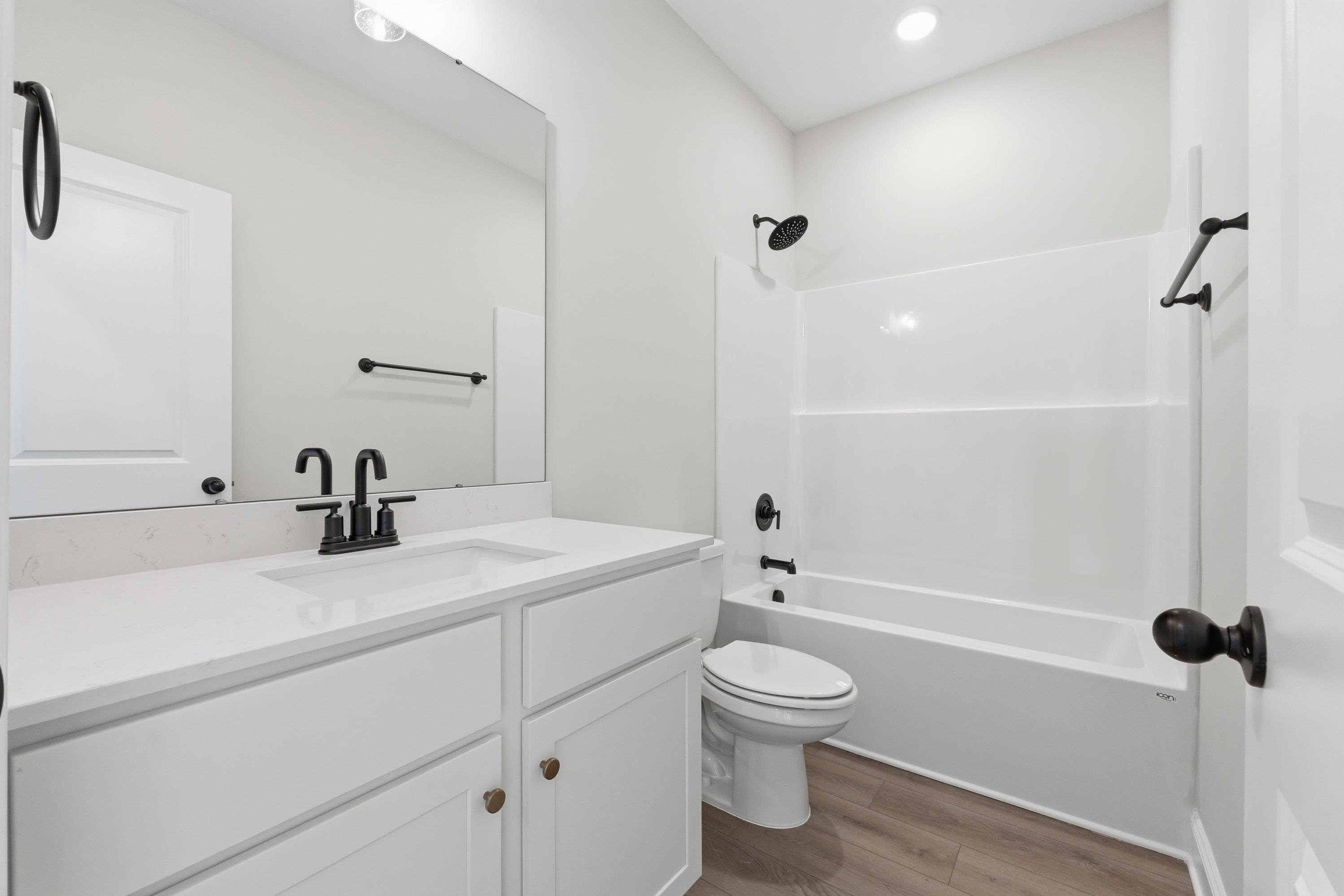 Modern bathroom in The Glen A featuring a white vanity, quartz countertops, and a tub-shower combo with matte black accents.