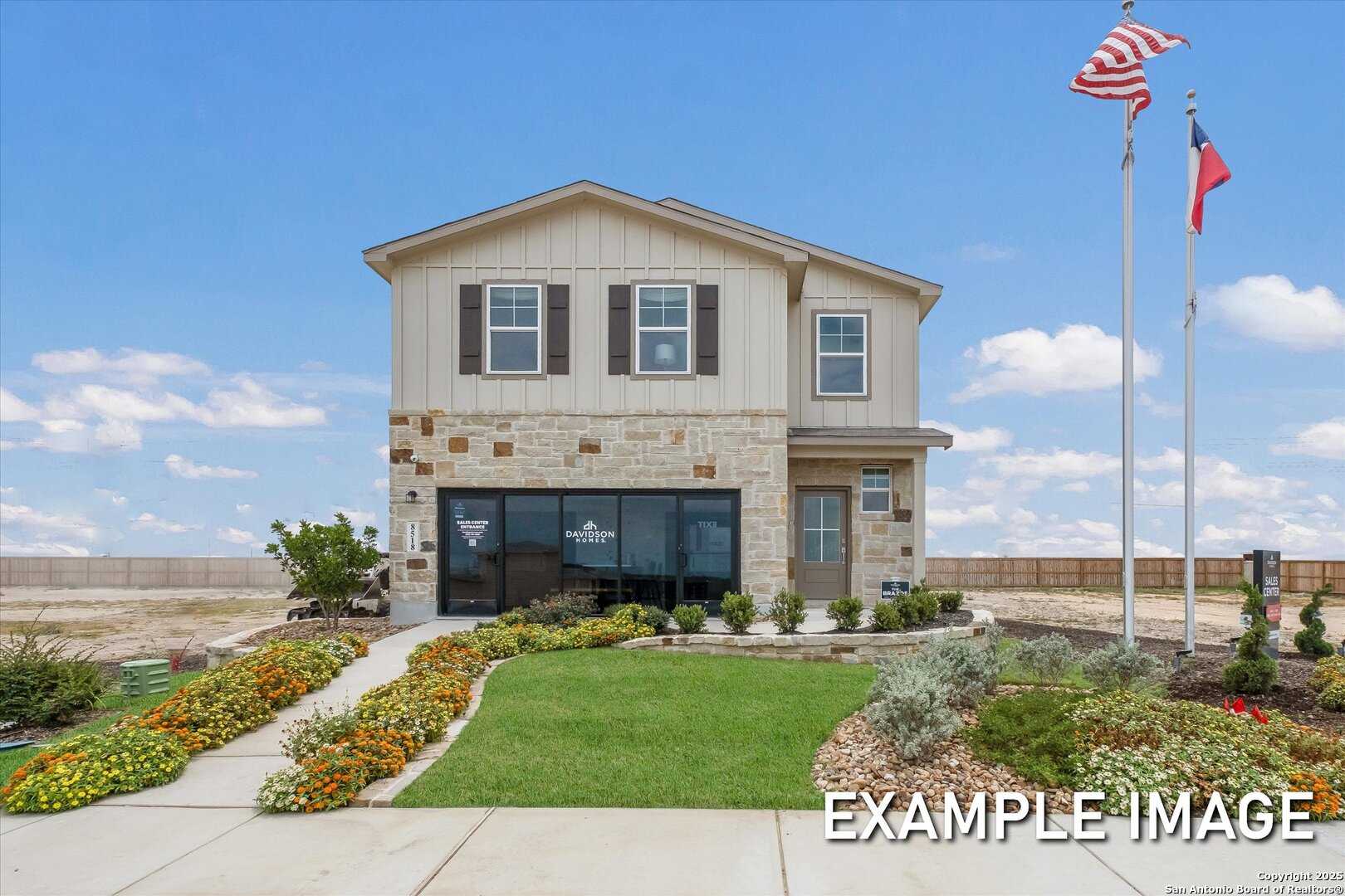 Two-story beige home exterior with stone accents, US and Texas flags, vibrant flower beds in Agave, San Antonio, Texas - Davidson Homes The Brazos C