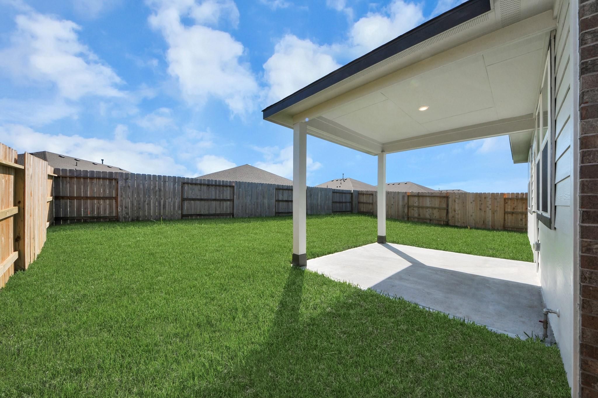 Covered back patio and fenced private backyard of The Colorado G floor plan by Davidson Homes in Emberly, Beasley, Texas.