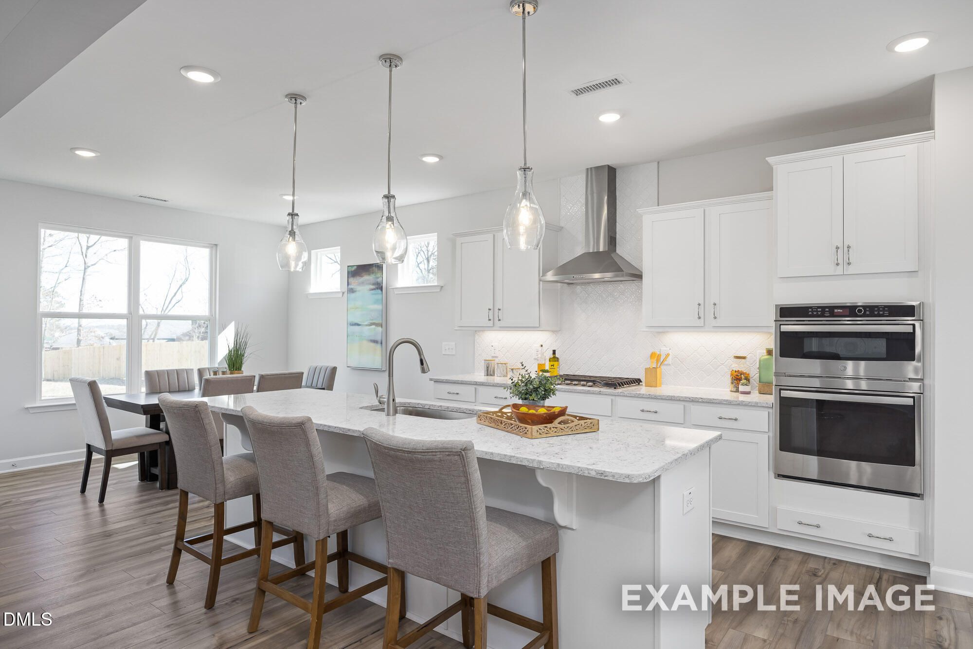 Open-concept kitchen with white cabinets, quartz island, stainless appliances, and pendant lights in Davidson Homes The Cypress B II, Angier, NC