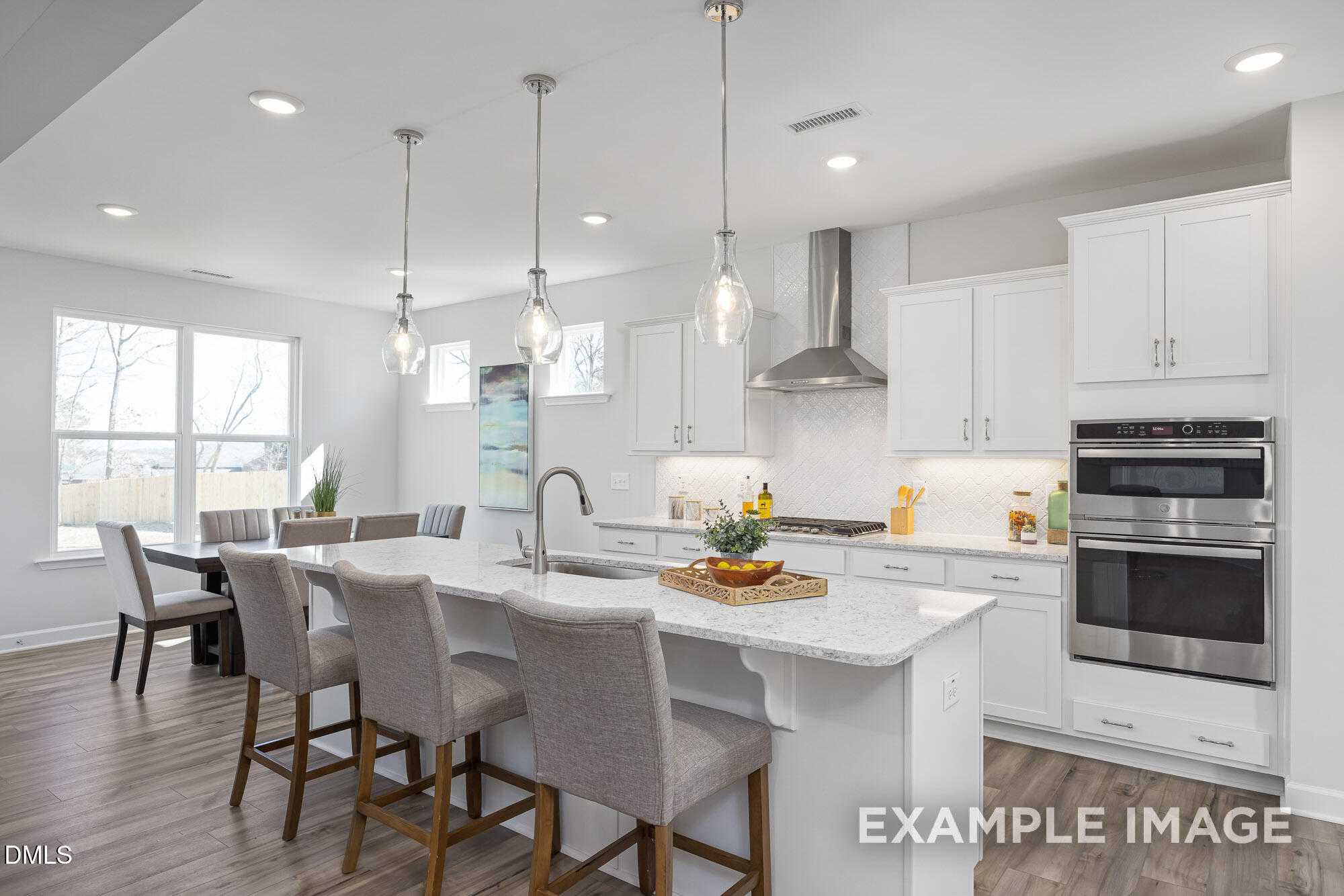 Open-concept kitchen with white cabinets, quartz island, stainless appliances, and pendant lights in Davidson Homes The Cypress B II, Angier, NC