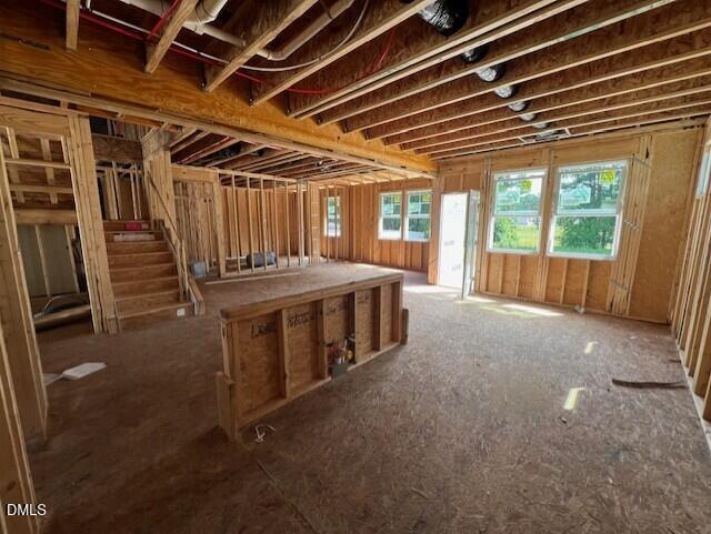 Open construction framing of The Willow D floor plan in Wellers Knoll, Lillington, NC, showing staircase and kitchen island.