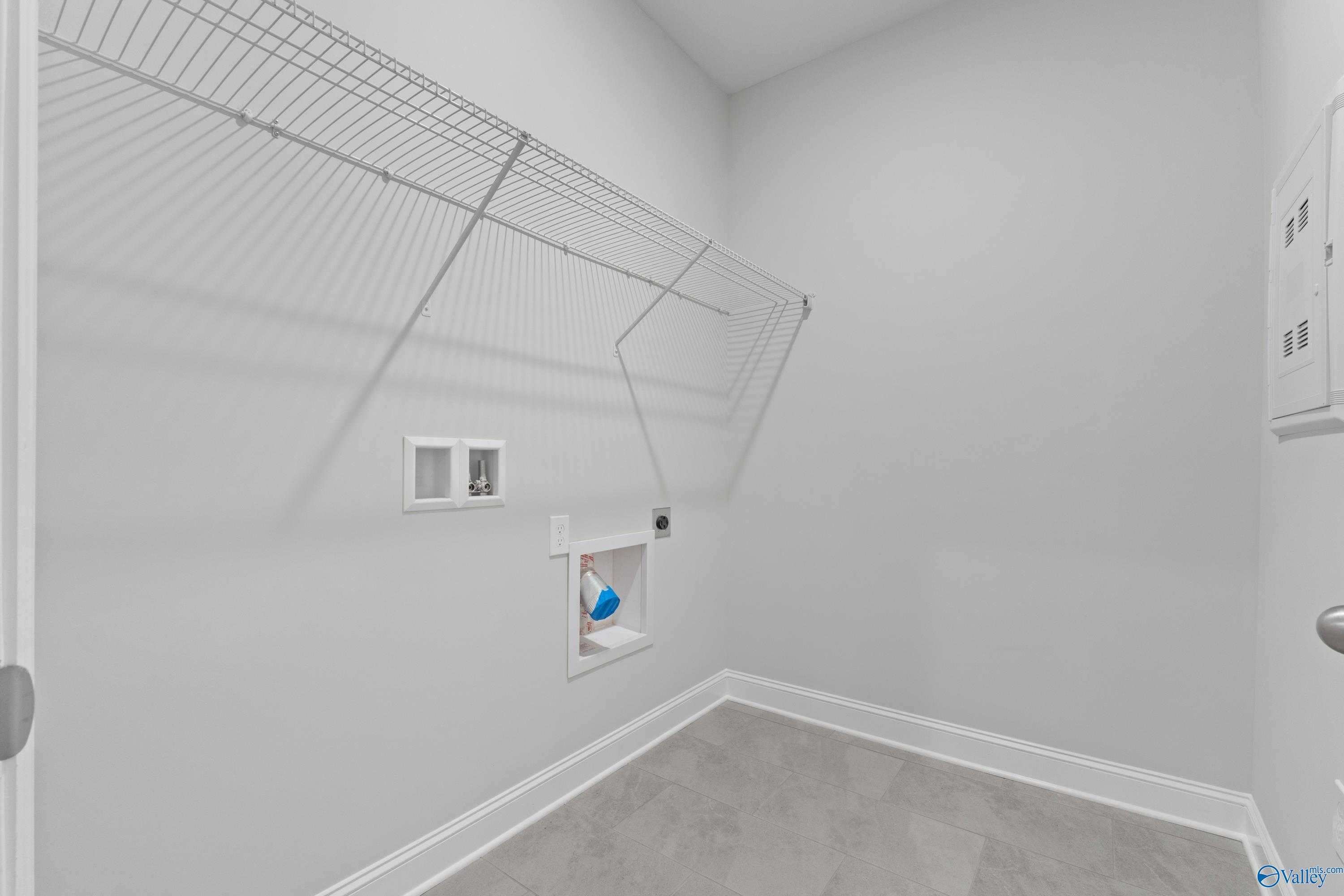 Spacious laundry room with wire shelving, utility sink, and washer hookups in Davidson Homes The Rockford B, Toney, AL