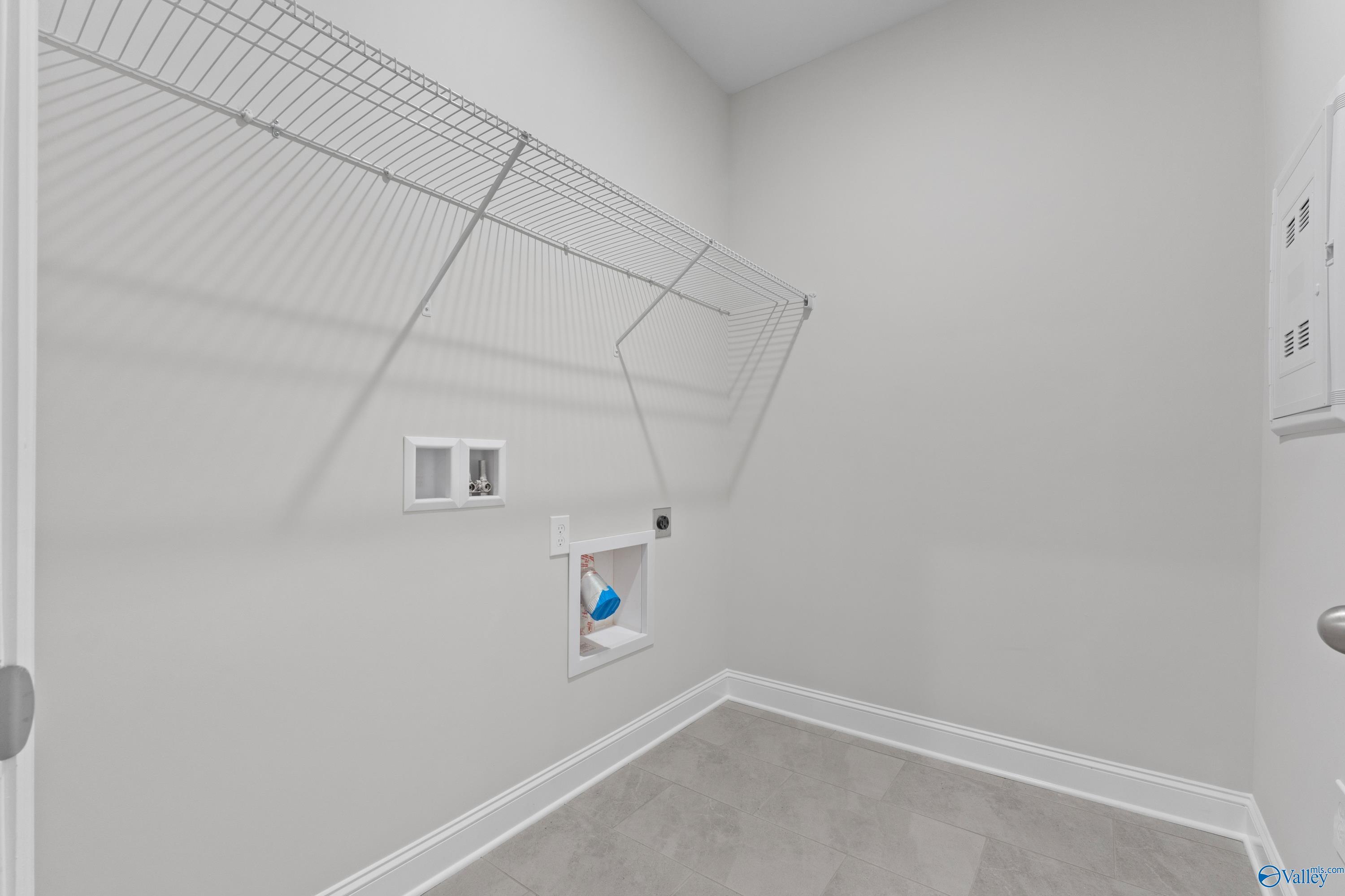 Spacious laundry room featuring wire shelving, utility sink, and washer-dryer hookups in Davidson Homes The Rockford B, Toney, Alabama
