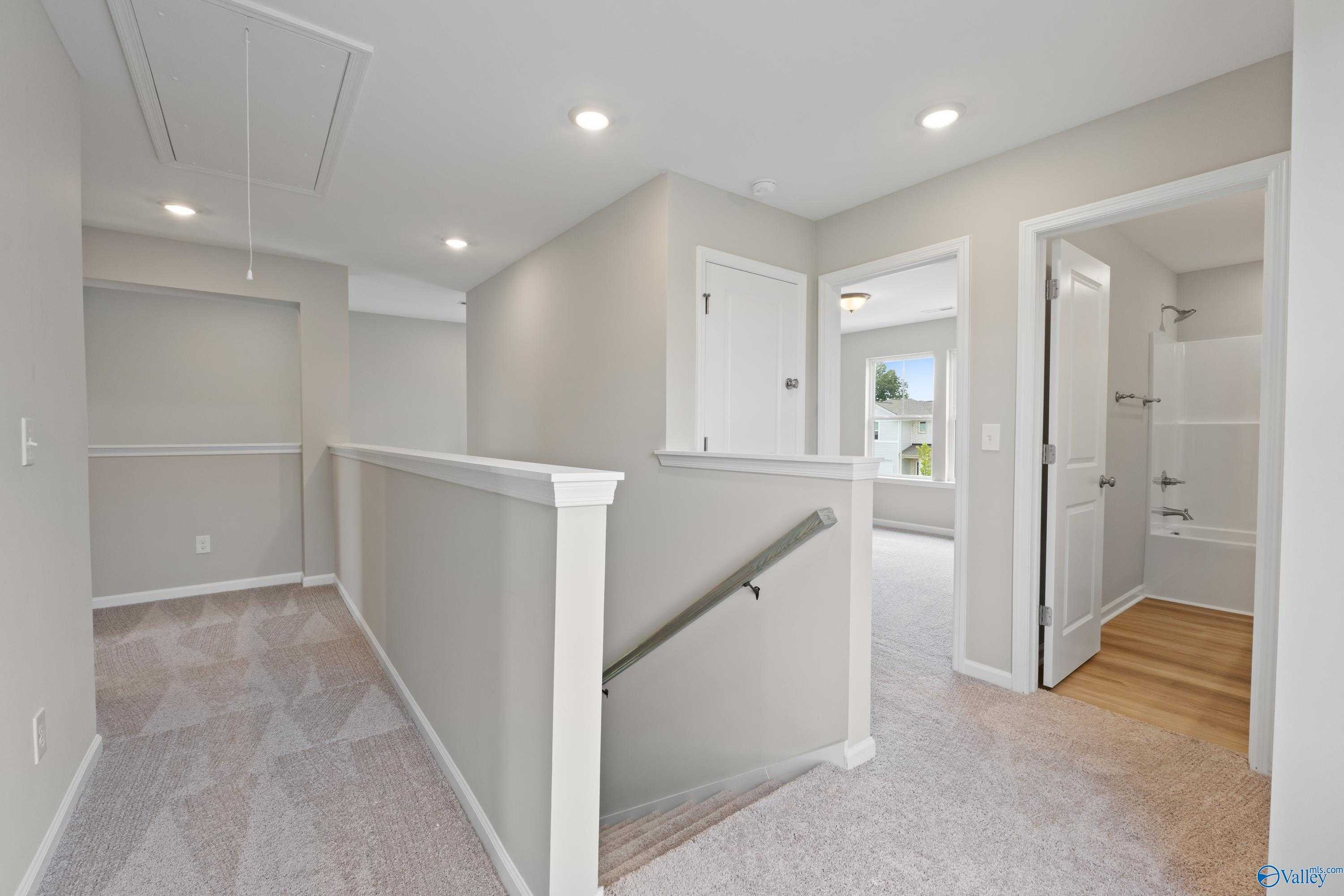 Spacious upstairs hallway with white railing overlooking stairs in 2-story The Augusta home, Evermore Homes, Evergreen Mill, Madison, Alabama