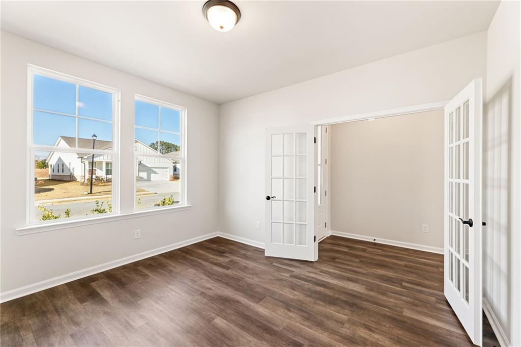 Bright study room with large windows overlooking neighborhood, hardwood floors, and open French doors in Davidson Homes Glenwood A, Loganville, GA