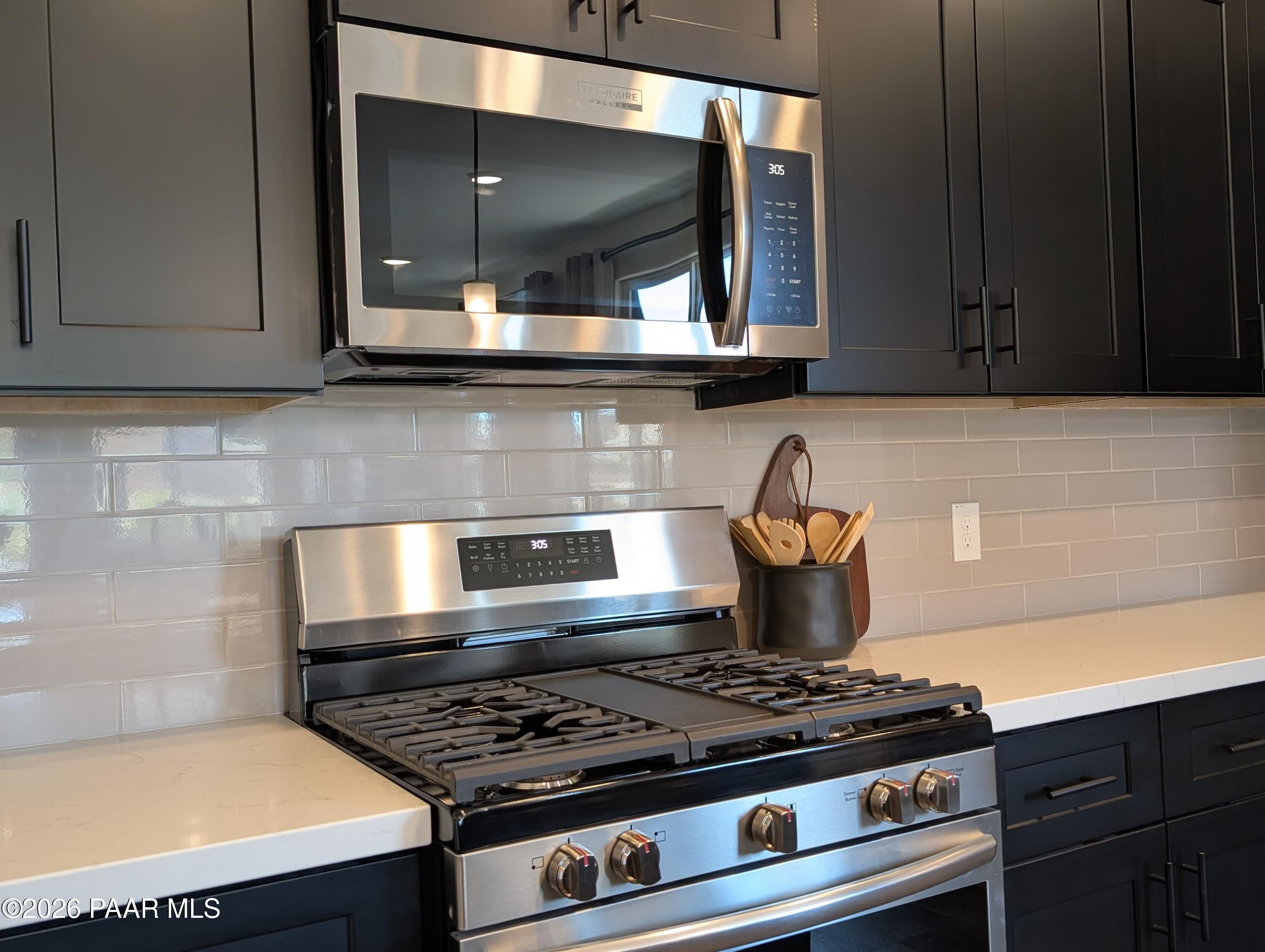 Modern kitchen with stainless steel appliances and dark cabinetry in The Boulder II H at South Ranch, Prescott, Arizona.
