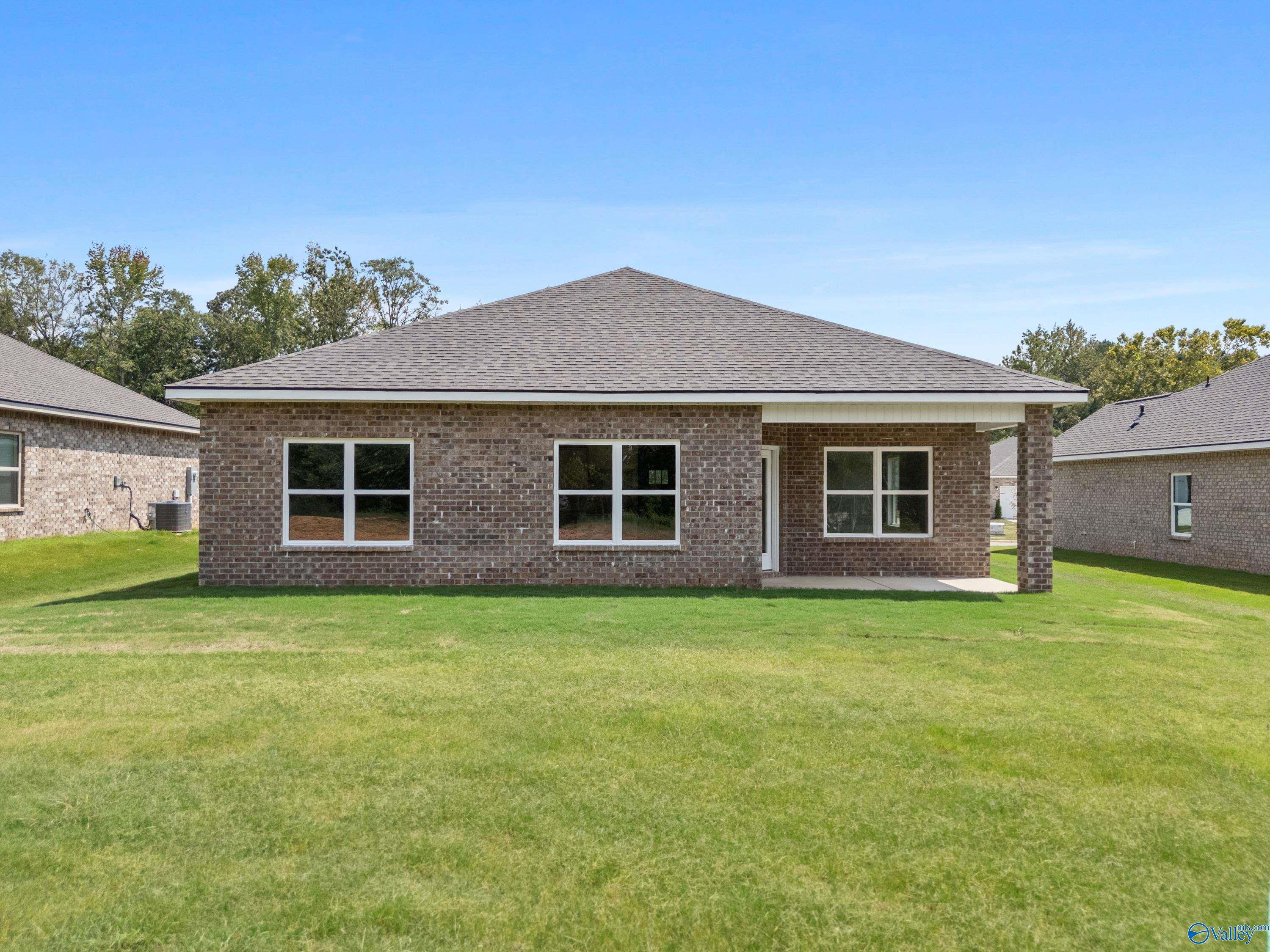 Rear brick exterior of The Franklin C 3-bedroom home with covered patio, large windows, and green lawn in Spragins Cove, Huntsville, Alabama
