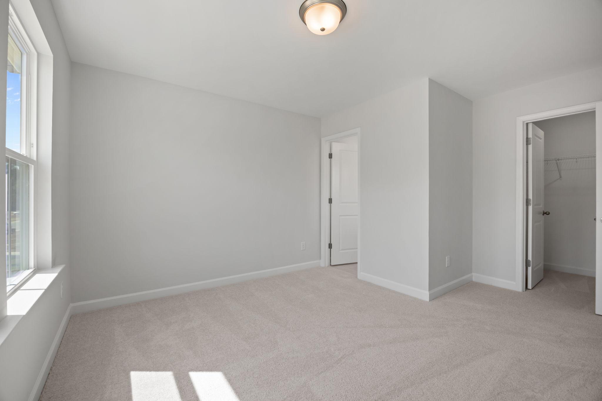 Spacious secondary bedroom in The Ashport B floor plan featuring neutral paint, soft carpeting, and a walk-in closet.