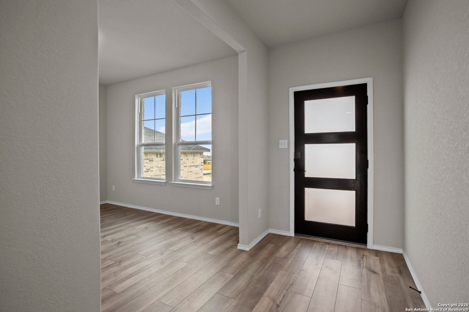 Bright entryway with frosted glass door, hardwood floors, and large windows in Davidson Homes The Douglas F, Comanche Ridge, San Antonio