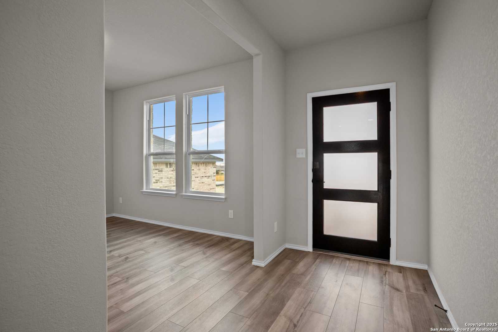 Bright entryway with frosted glass door, hardwood floors, and large windows in Davidson Homes The Douglas F, Comanche Ridge, San Antonio