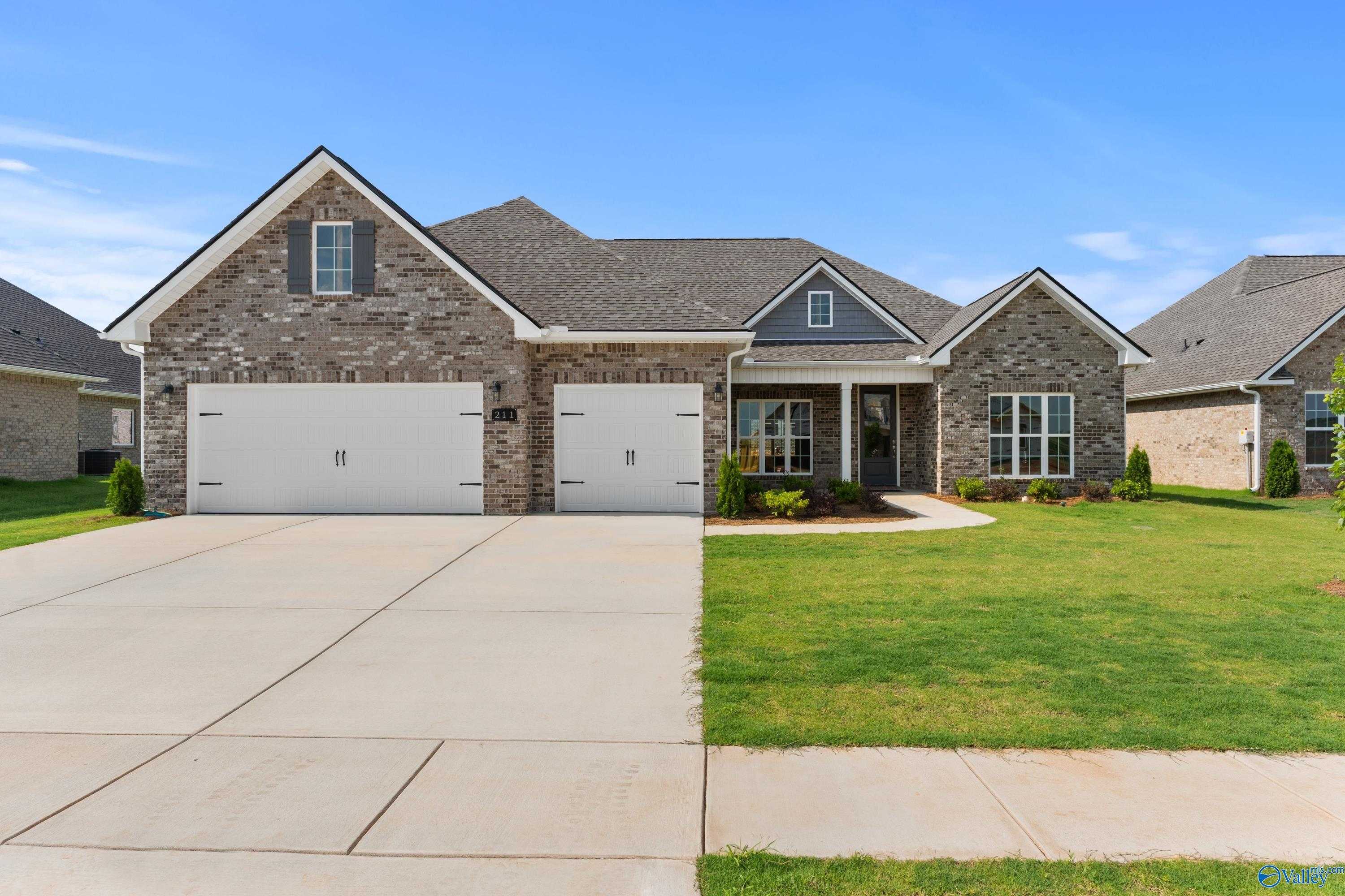 The Finleigh single-story brick home with 3-car garage, covered porch, and lush landscaping in Kendall Farms, Toney, Alabama