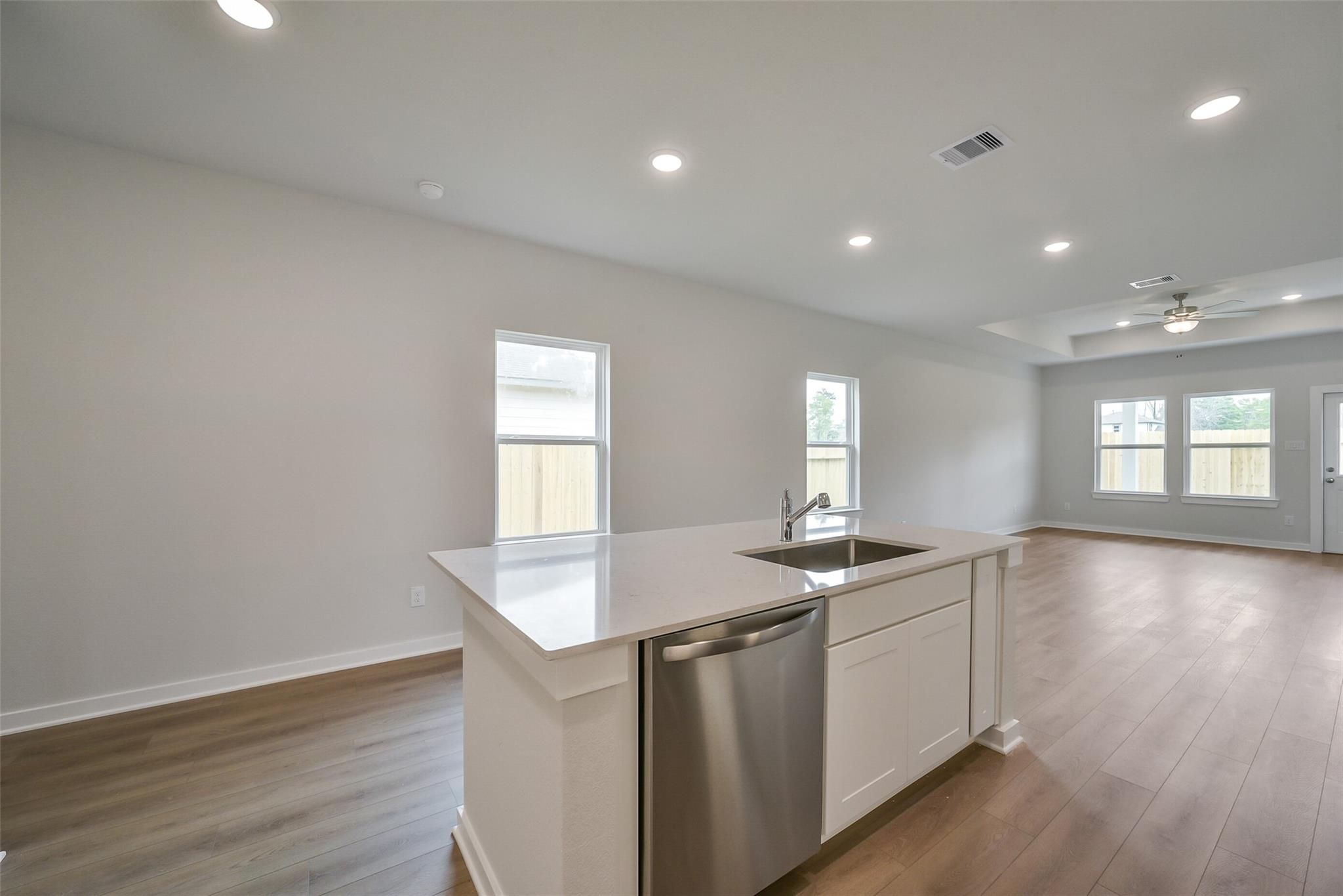 Modern open-concept kitchen with white island, stainless dishwasher, and sink in The Frio F floor plan by Davidson Homes, Conroe, TX