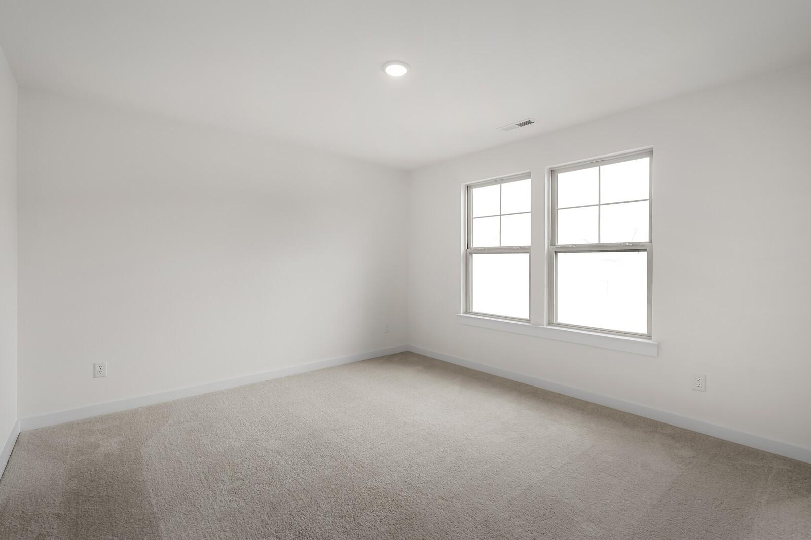 Spacious empty bedroom with beige carpet, white walls, and double windows in Davidson Homes The Willow C, Gallatin, TN