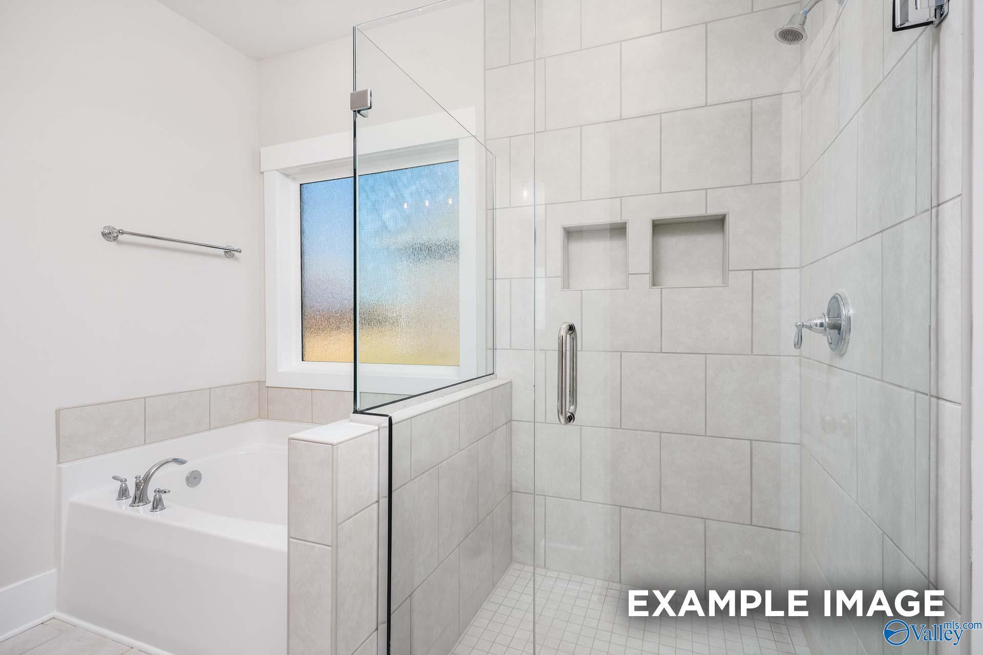 Luxurious master bathroom with frameless glass shower, soaking tub, and frosted window in Davidson Homes The Harrison, Decatur AL