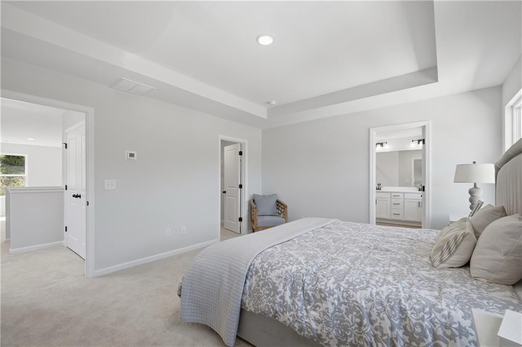 Bright tray-ceiling master bedroom with plush bedding and en-suite bath in Davidson Homes' Hartwell C plan, The Bluffs, Canton, GA