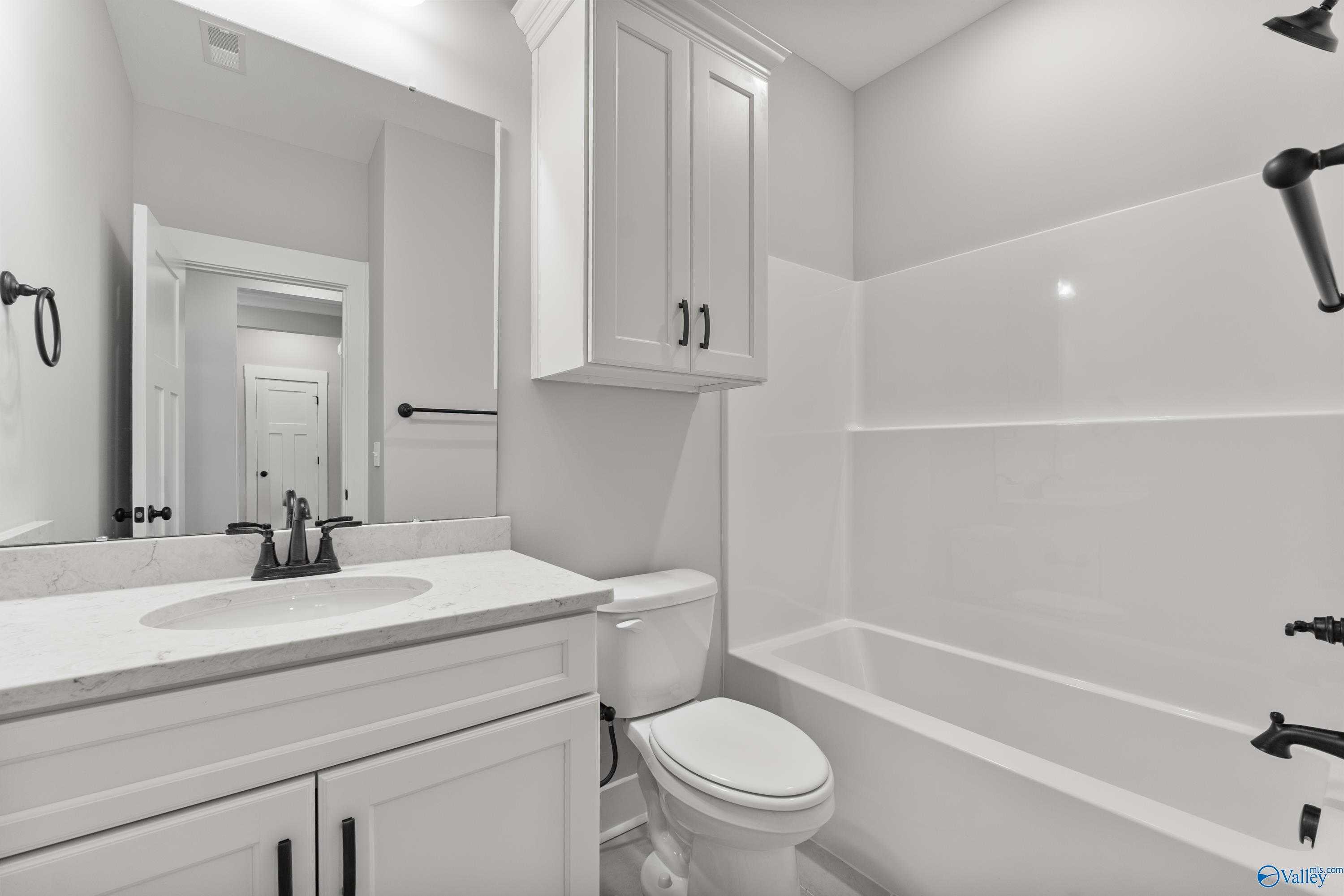 Modern bathroom with white shaker cabinets, marble vanity, tub-shower combo and black fixtures in Davidson Homes The Arcadia, Huntsville AL
