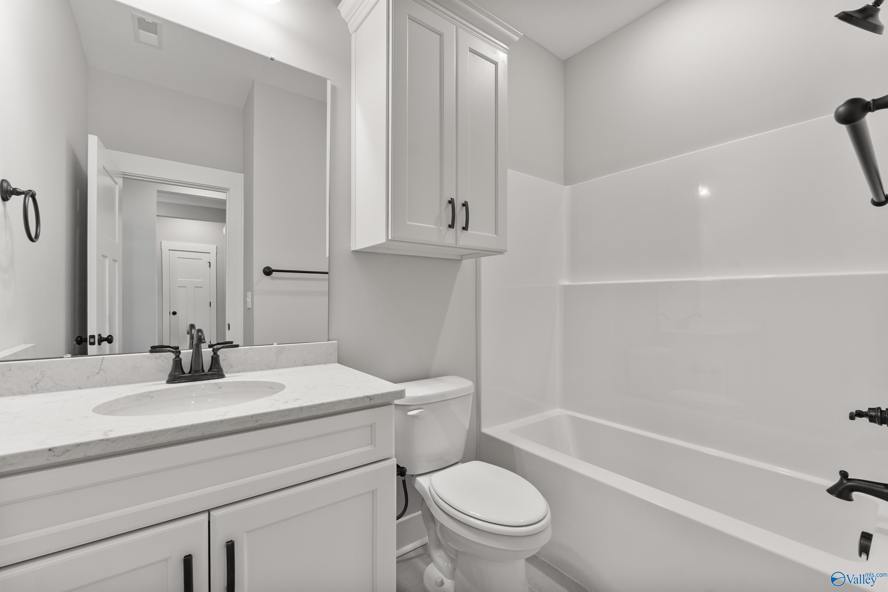 Modern bathroom with white shaker cabinets, marble vanity, tub-shower combo and black fixtures in Davidson Homes The Arcadia, Huntsville AL