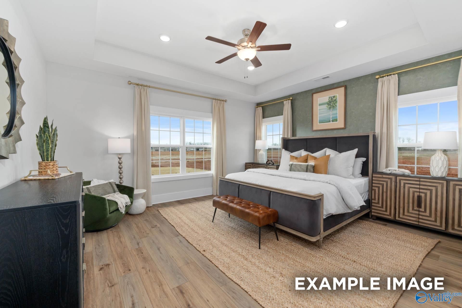 Elegant master bedroom with king bed, tray ceiling, ceiling fan, and large windows in Davidson Homes The Finleigh, Decatur, AL