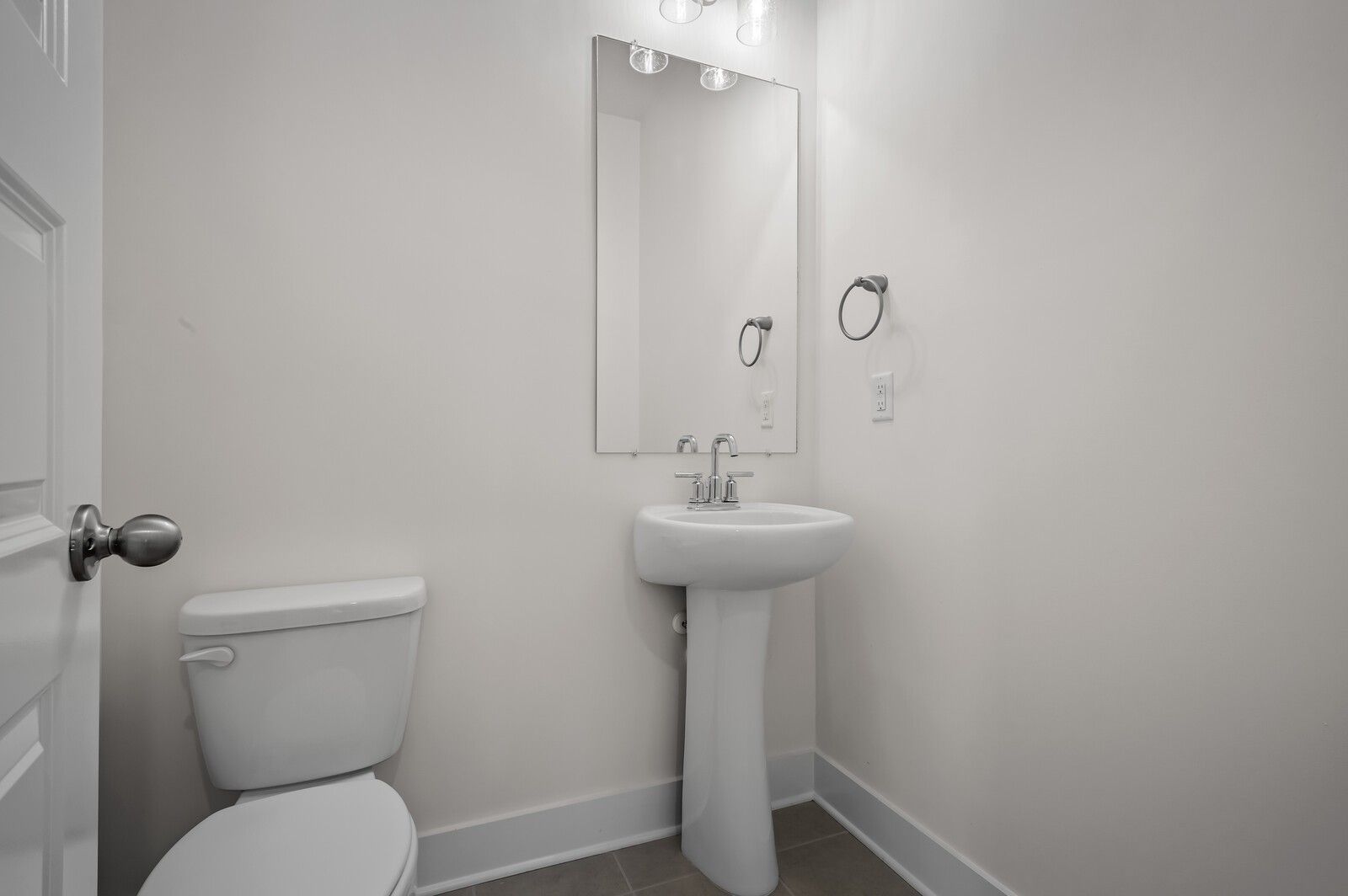 Modern half-bath with pedestal sink and wall mirror in The Ash A floor plan at Woods Crossing, Gallatin, Tennessee.