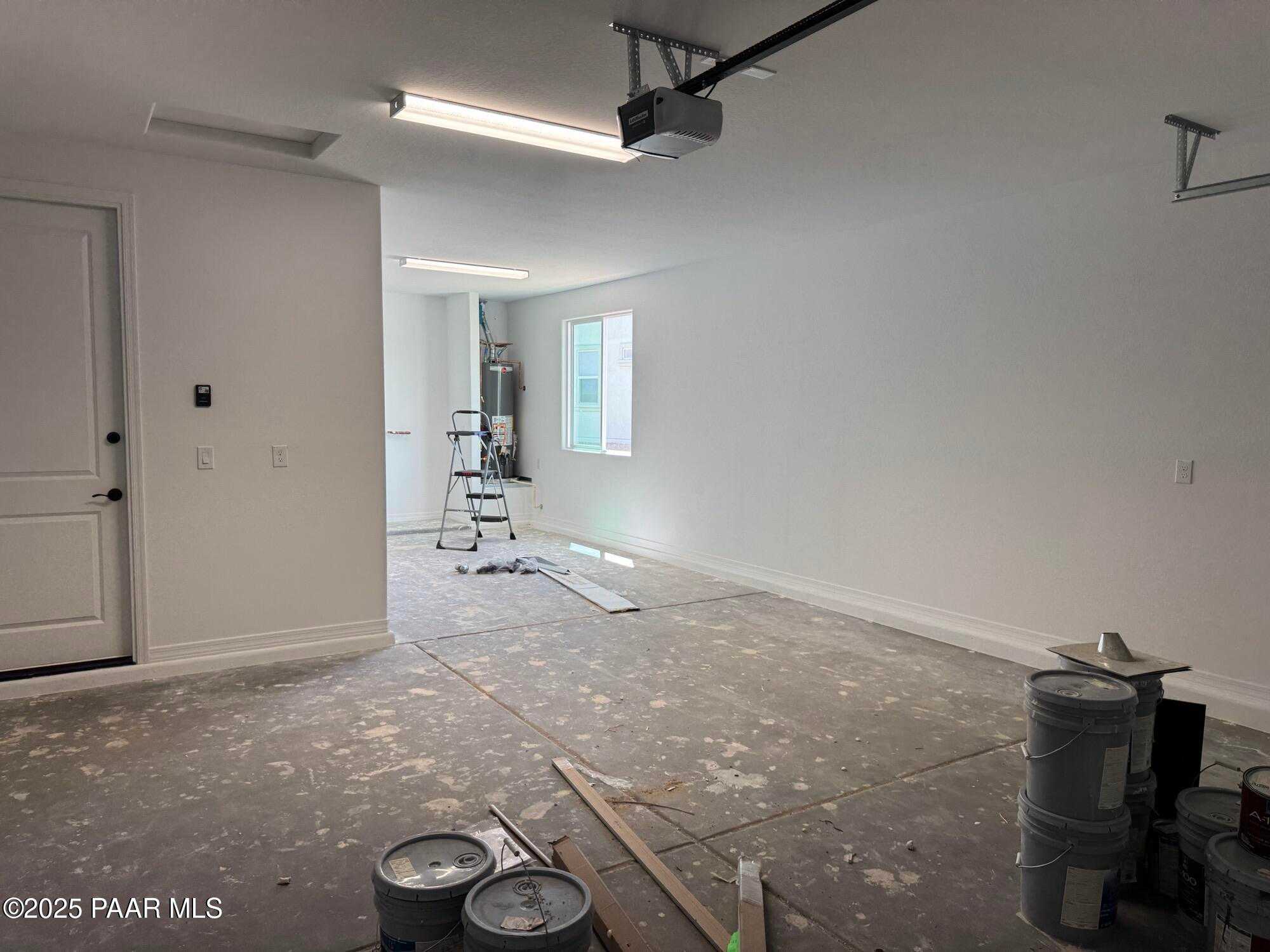 Spacious 3-car garage under construction with ladders, paint cans, and drywall in Davidson Homes The Sheridan II B, Westwood, Prescott, Arizona