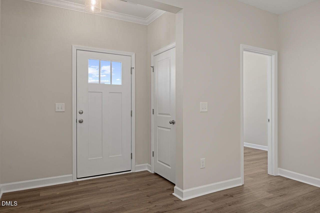 Bright entryway with white craftsman-style door and luxury vinyl plank flooring in The Alexander C home, Knightdale, NC.
