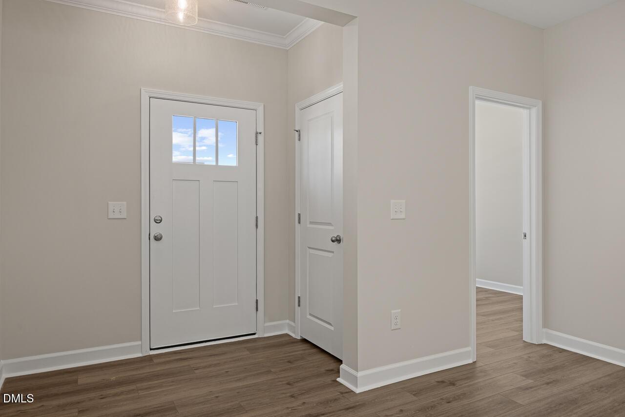 Bright entryway with white craftsman-style door and luxury vinyl plank flooring in The Alexander C home, Knightdale, NC.
