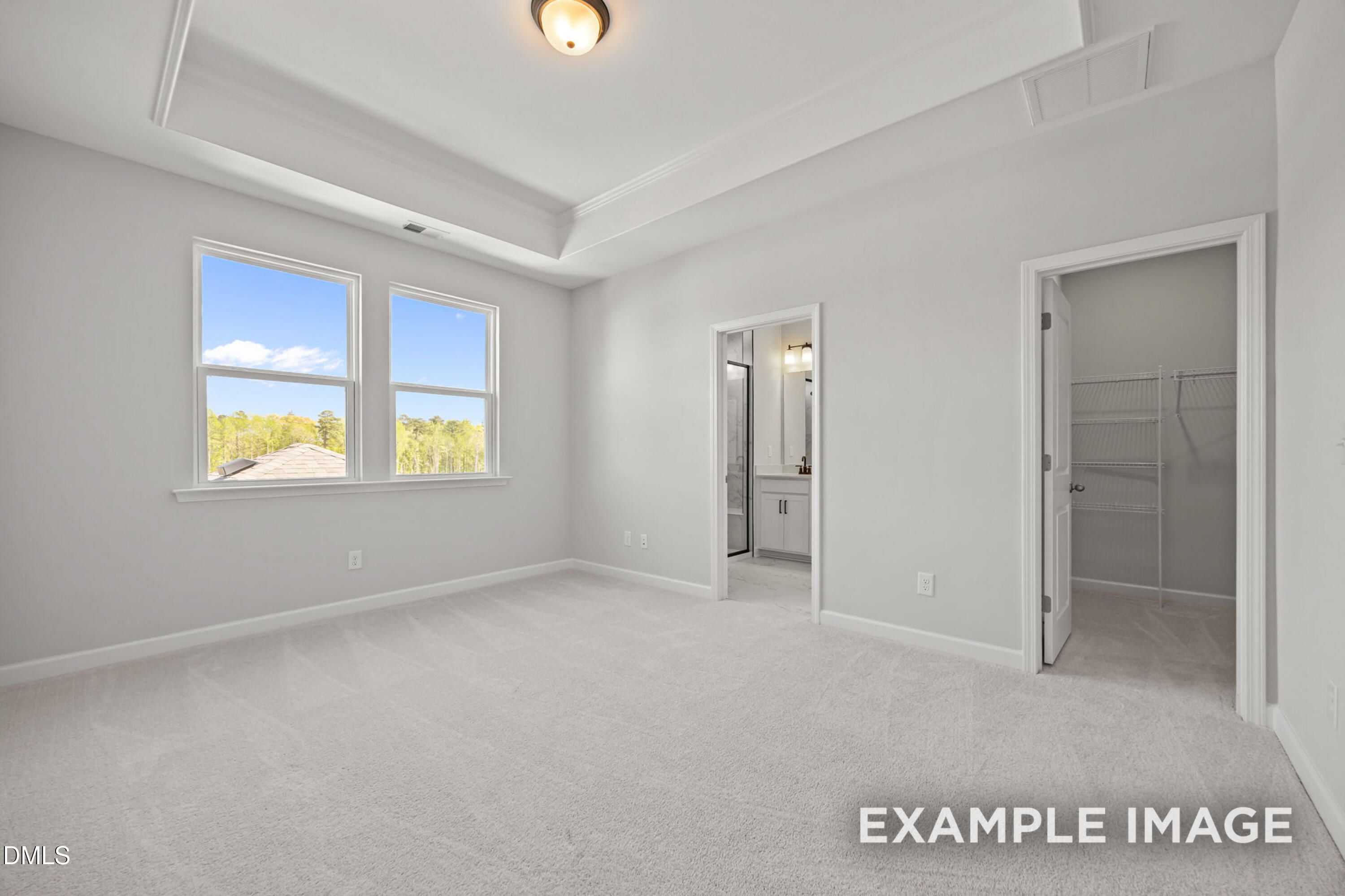 Primary bedroom with tray ceiling, en-suite bath, and walk-in closet in The Alexander B at Forestville Yard, Knightdale, NC.