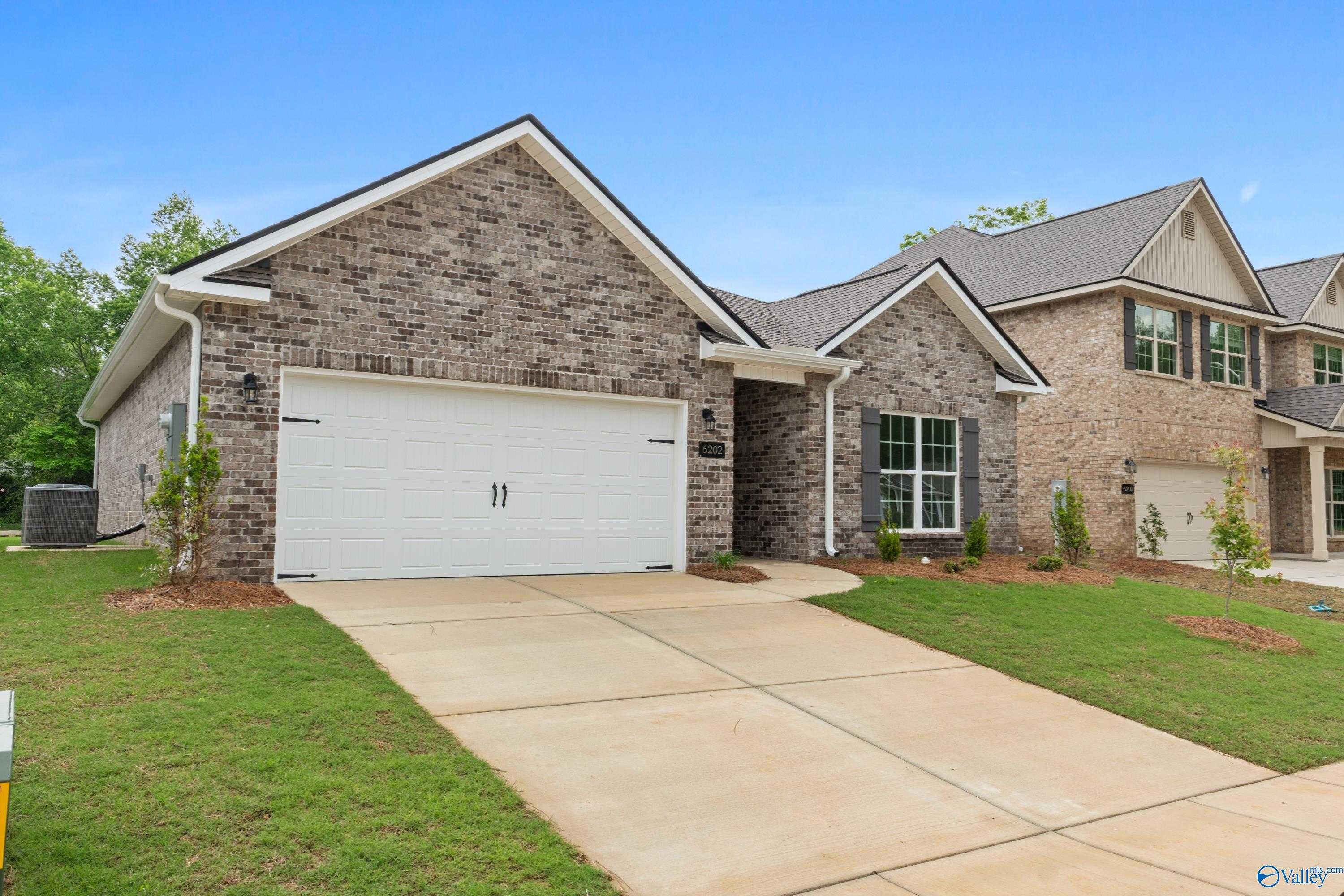 Brick ranch home with gabled roof, white 2-car garage, and landscaped yard in Jaguar Hills, Huntsville, Alabama