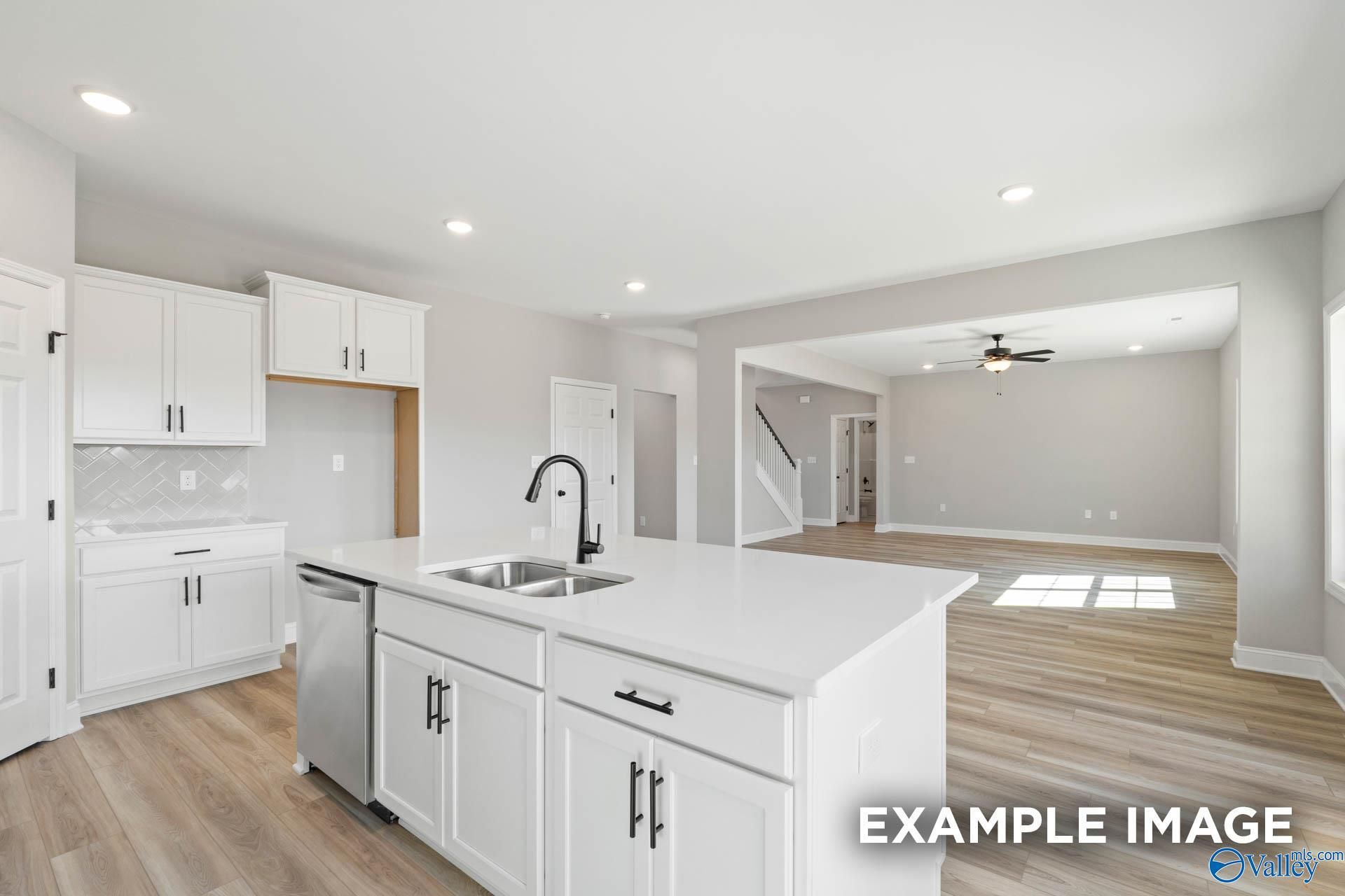 Modern white kitchen island with stainless sink and faucet in The Madison D plan at Evergreen Mill, Madison, Alabama.