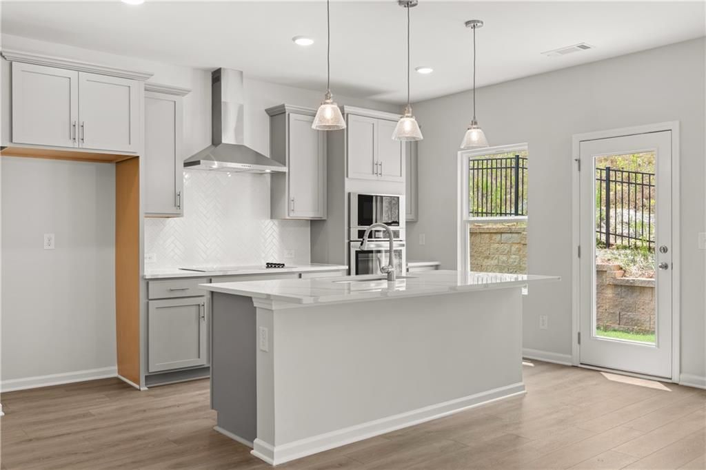 Modern kitchen with white island, herringbone backsplash, and pendant lighting in The Burton A home at The Bluffs, Canton.