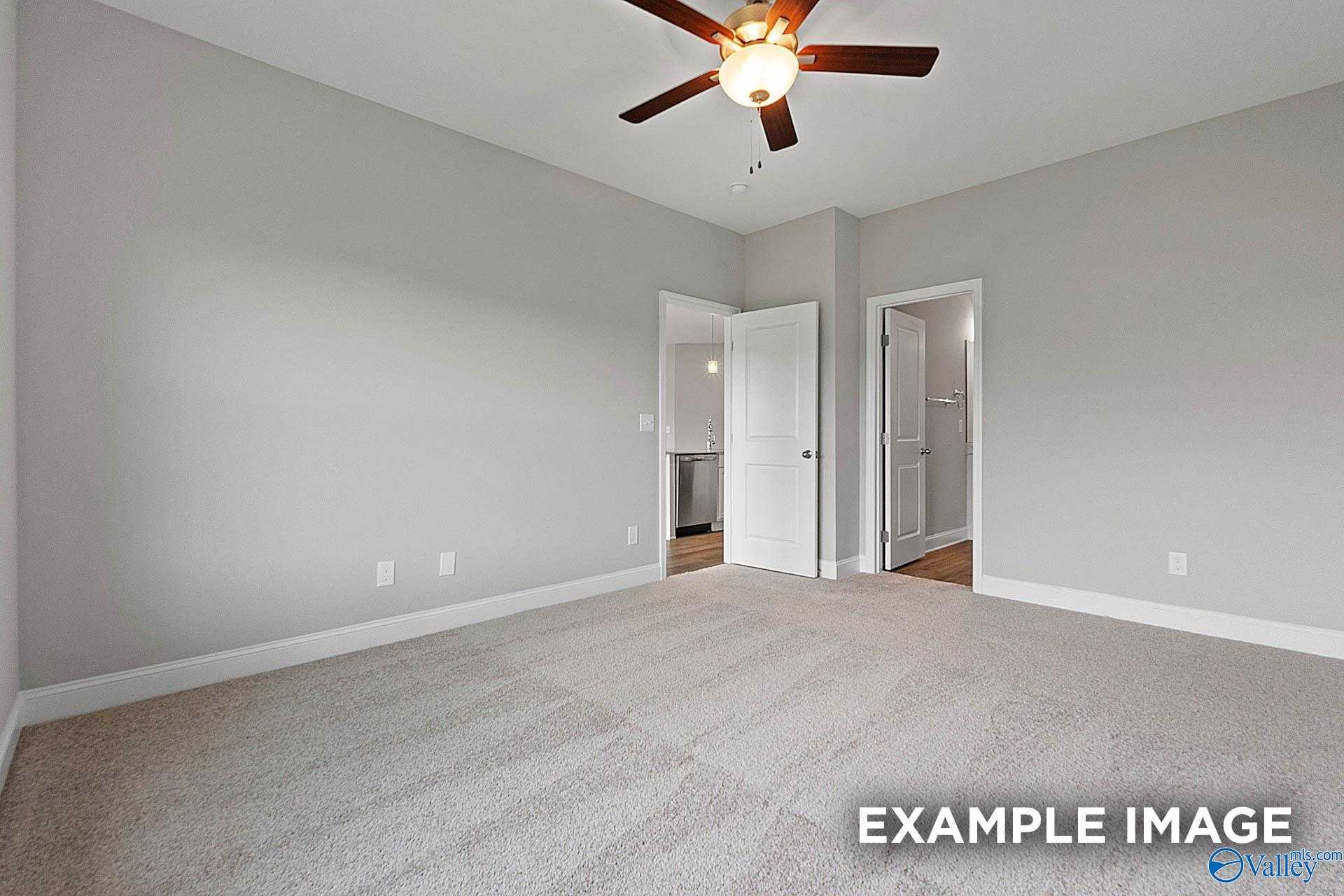 Master bedroom with ceiling fan, gray walls, carpeted floor, open bathroom door in Davidson Homes The Franklin E, Hazel Green, Alabama